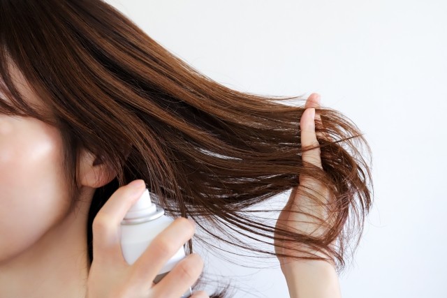 ヘアスプレーをしている女性