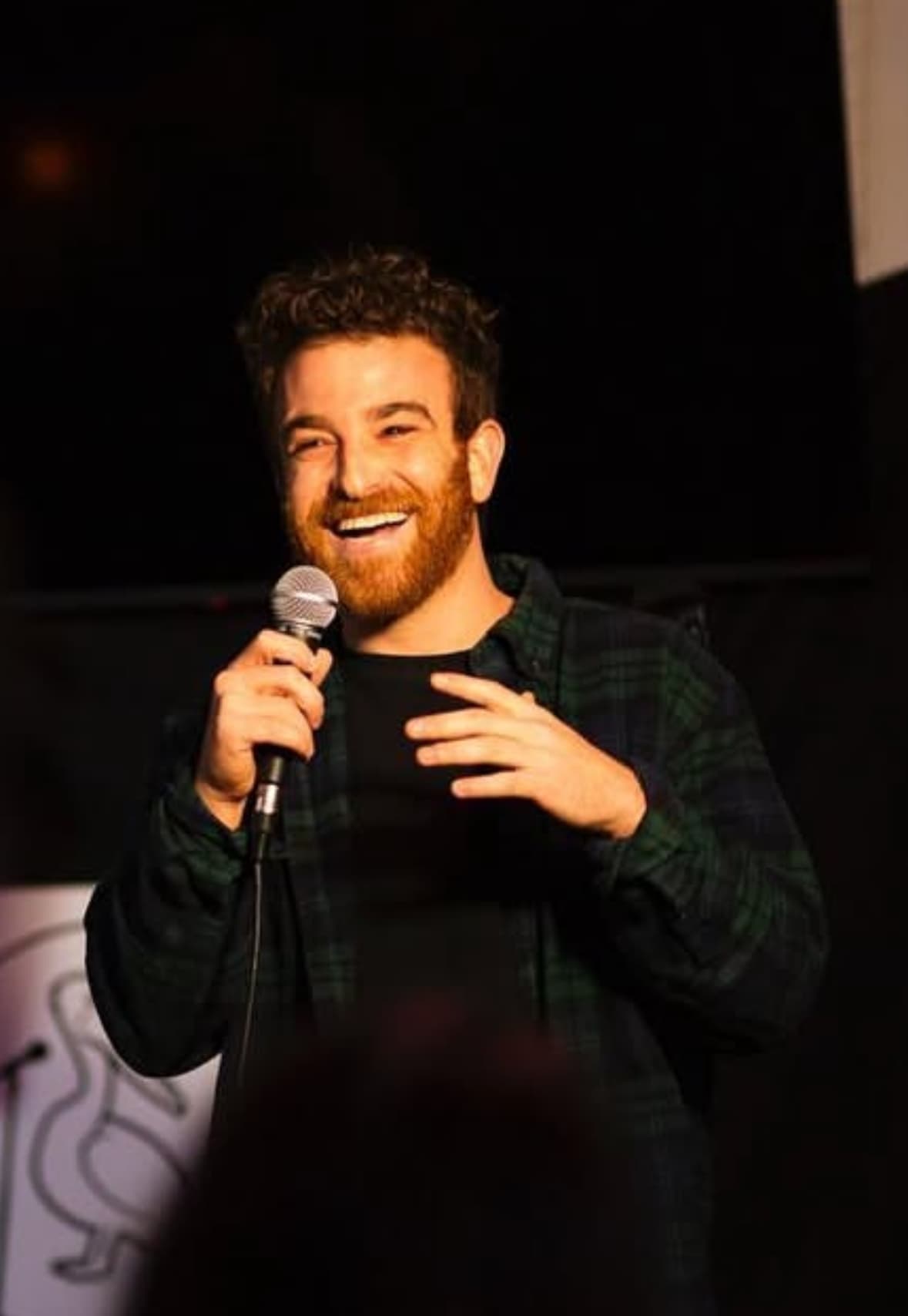 Jake Polin performing on stage in front of a live comedy audience