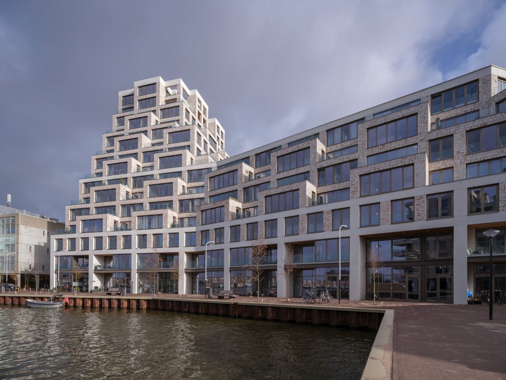 Modern appartementencomplex aan het water met getrapte structuur en bakstenen