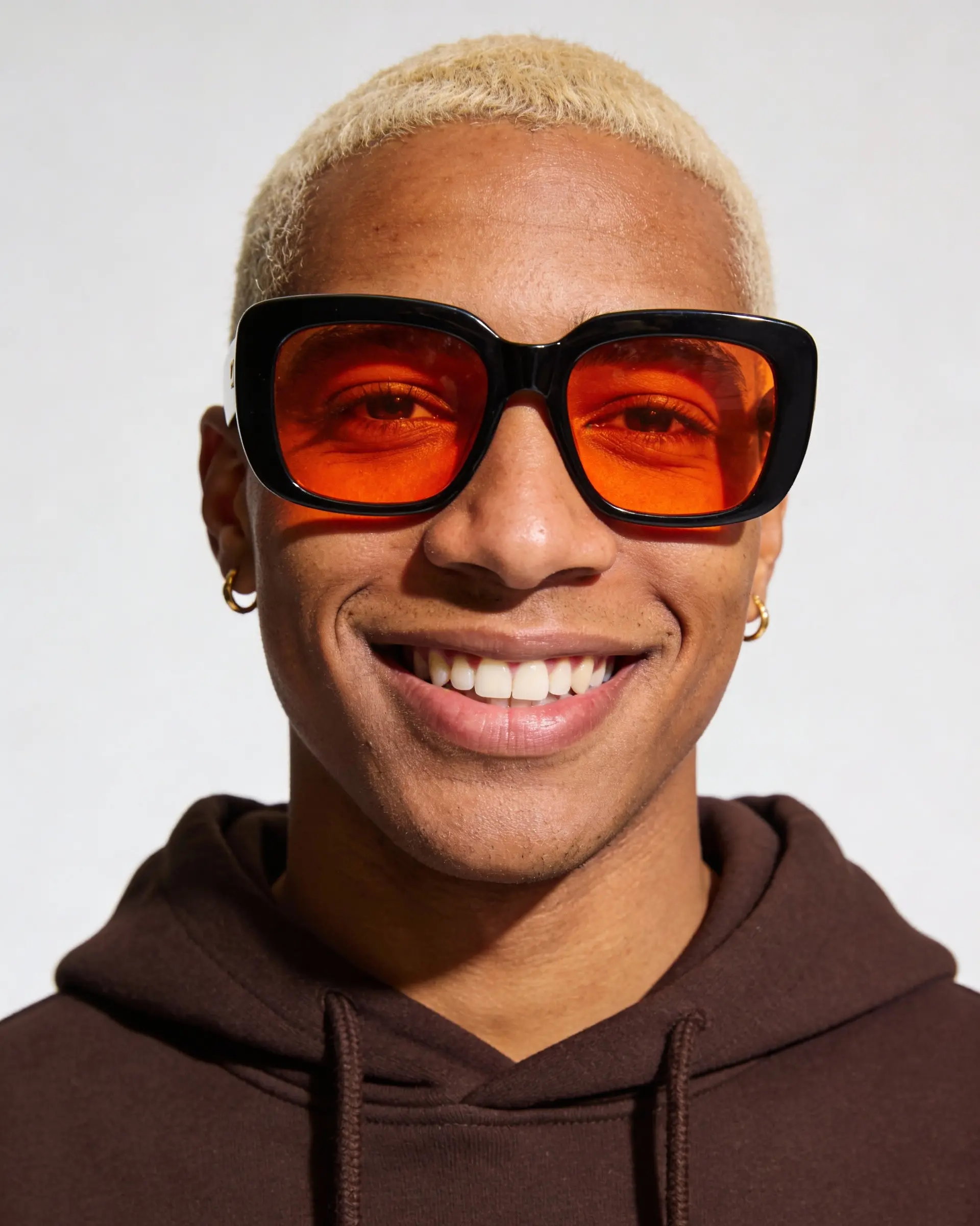 Portrait of a smiling person wearing orange-tinted sunglasses