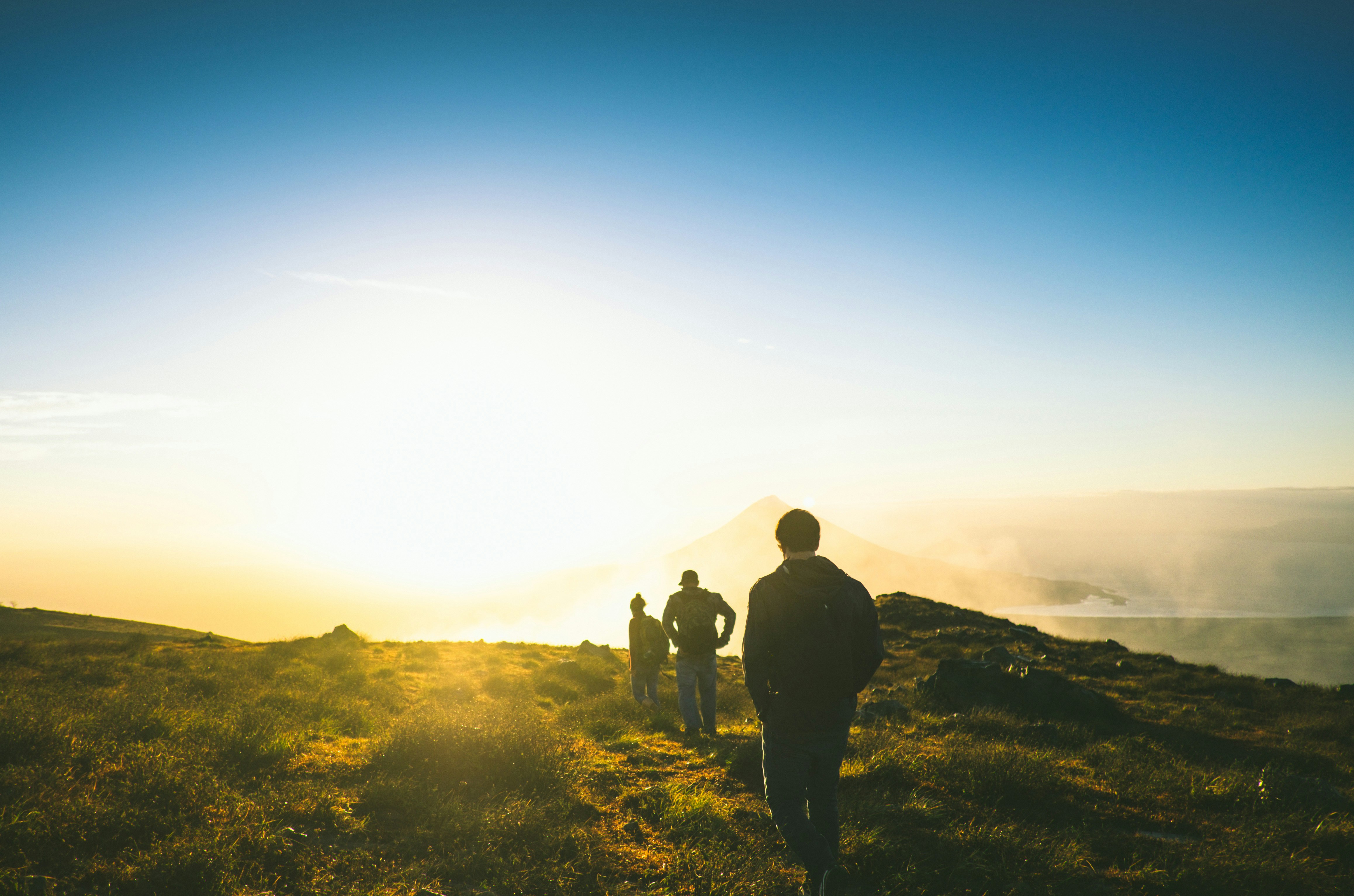 A few people walking over the peak of a mountain