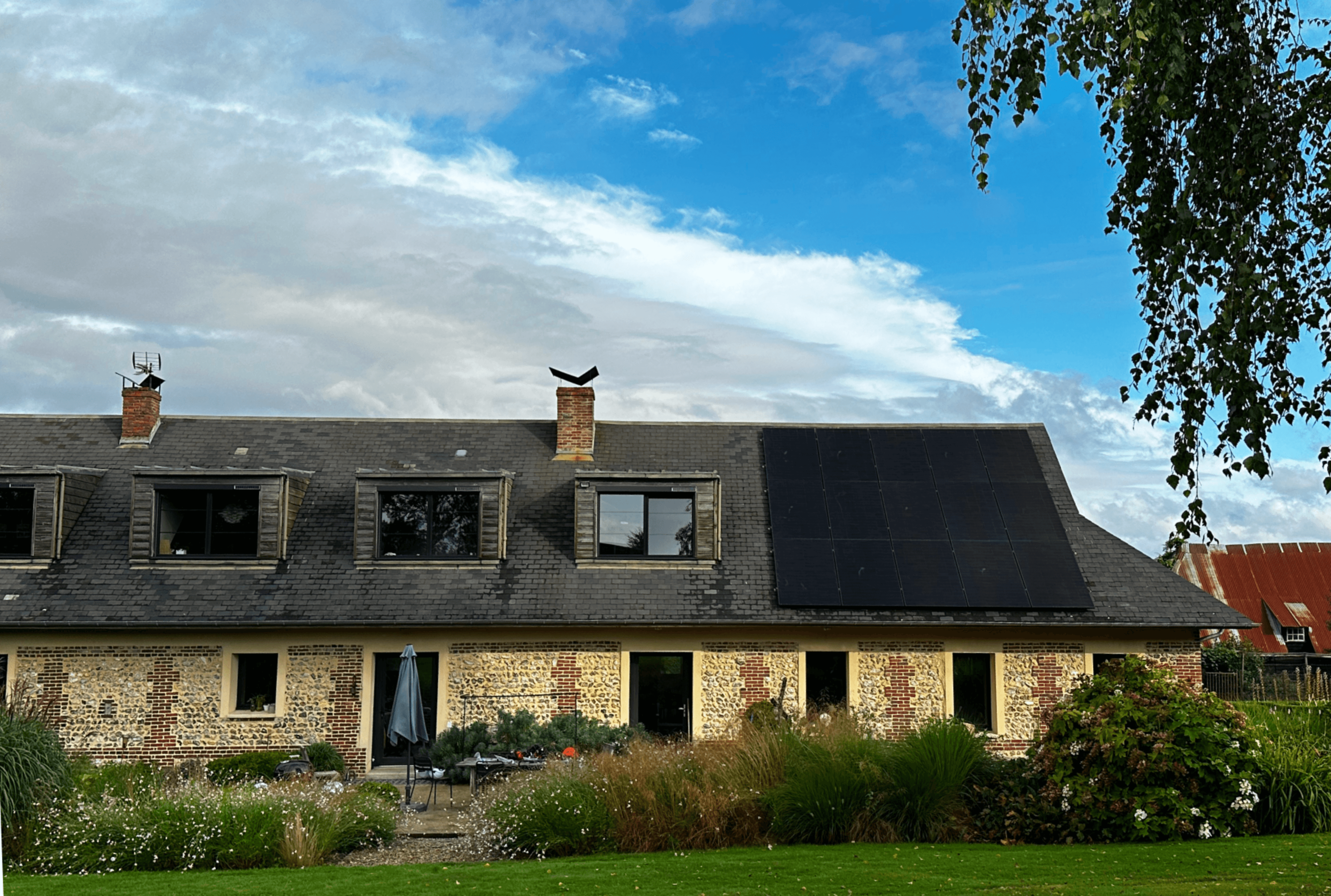 Une technicien Solarock installe des panneaux solaires sur le toit d’une maison dans un village en france.