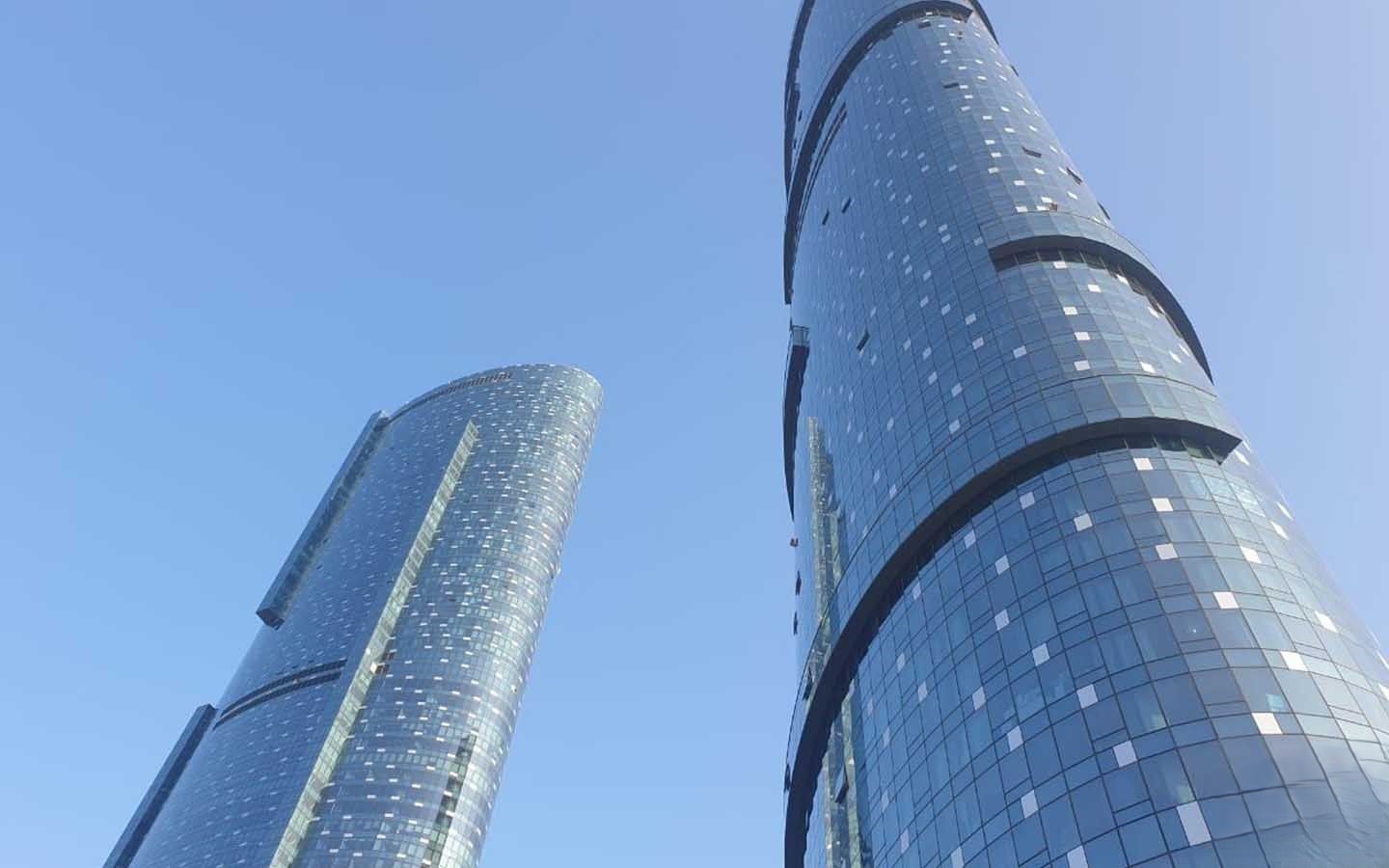 Twin glass towers reaching into a clear blue sky, representing high-end real estate portfolio opportunities.