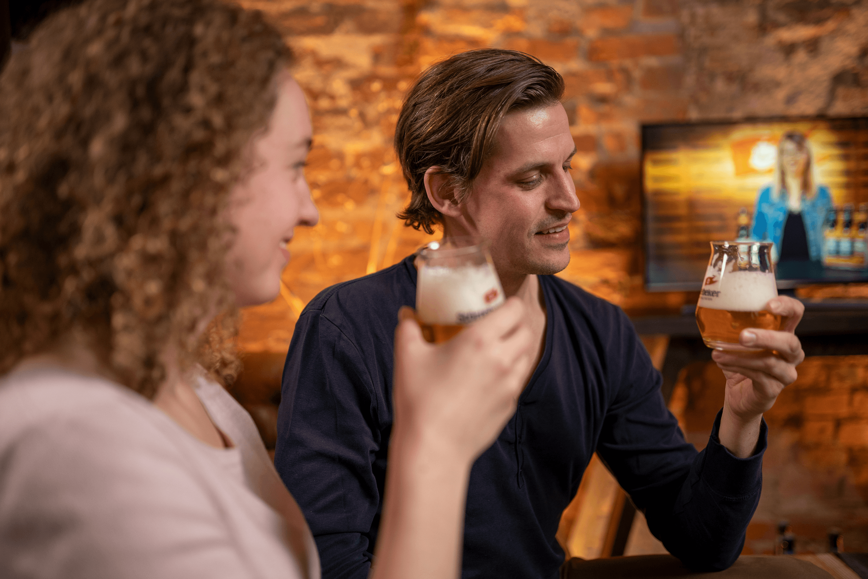 Man and woman holding and looking at beer glasses.
