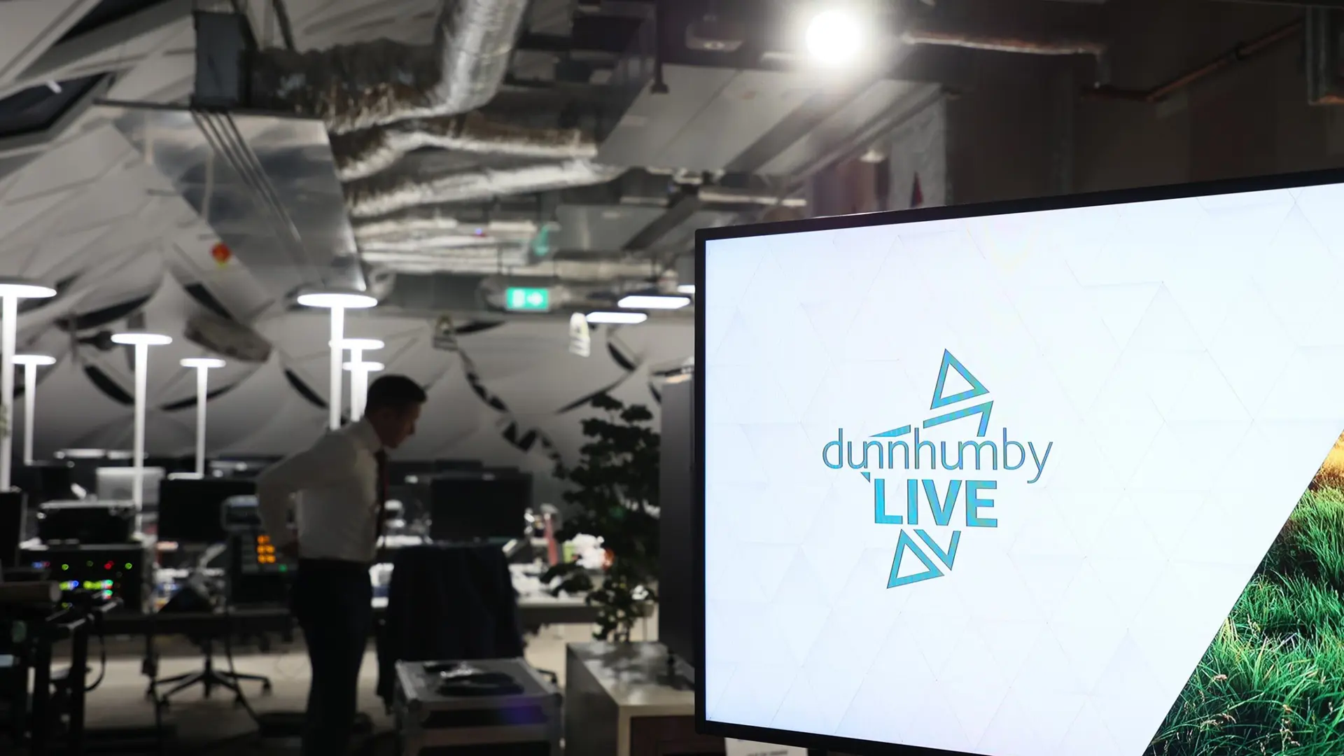 Large screen inside dunnhumby’s London office displaying ‘dunnhumby Live’ branding during a live broadcast setup.