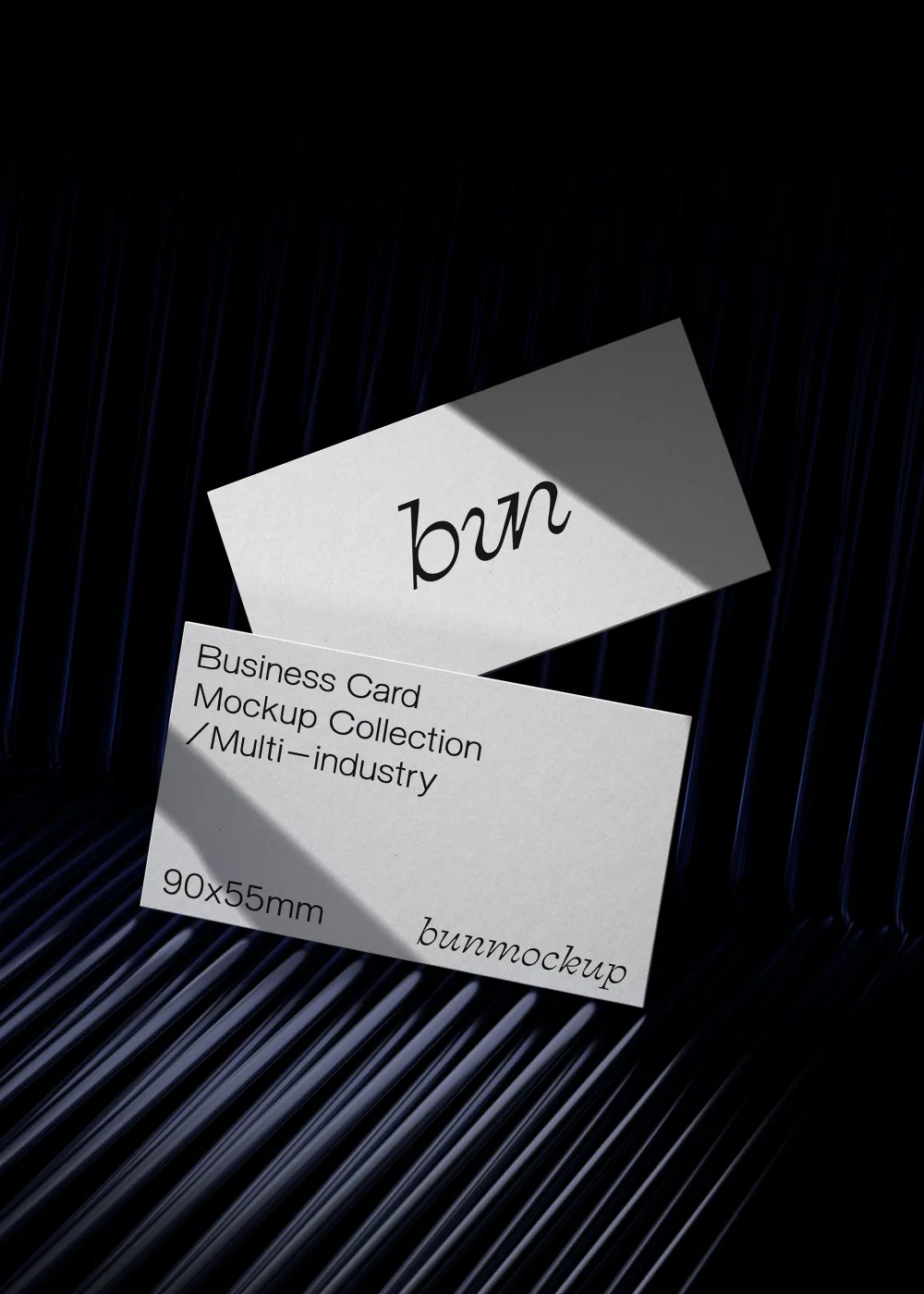 Elegant business card mockup featuring two white cards with black text placed diagonally, illuminated by a soft shadow. Background showcases deep blue textured ridges, adding depth.