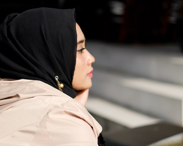 A woman wearing a black hijab in profile view with a calm, peaceful expression, representing Muslim healthcare workers during Ramadan