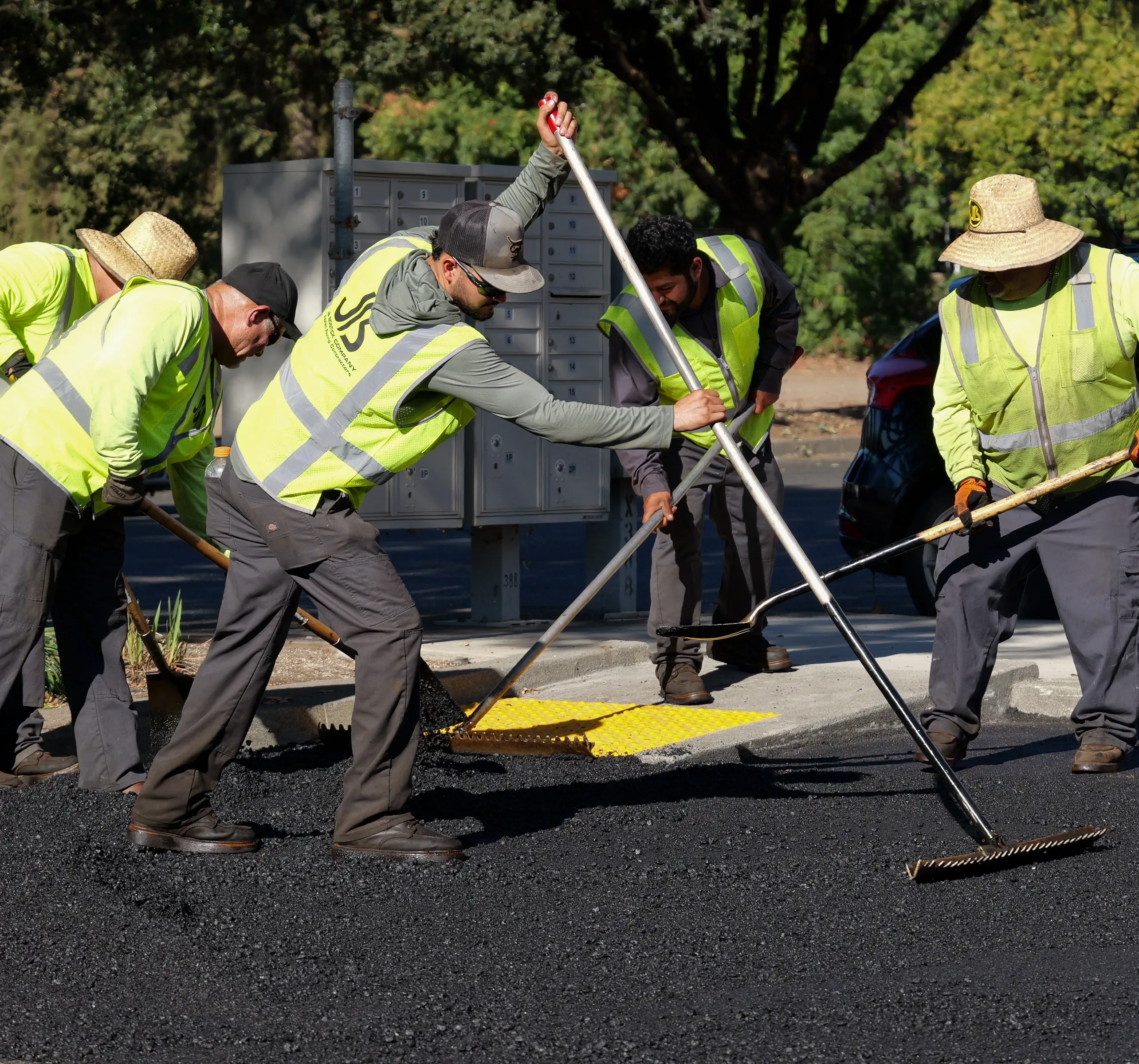 Asphalt crew raking and shoveling asphalt pavement to prep for compaction