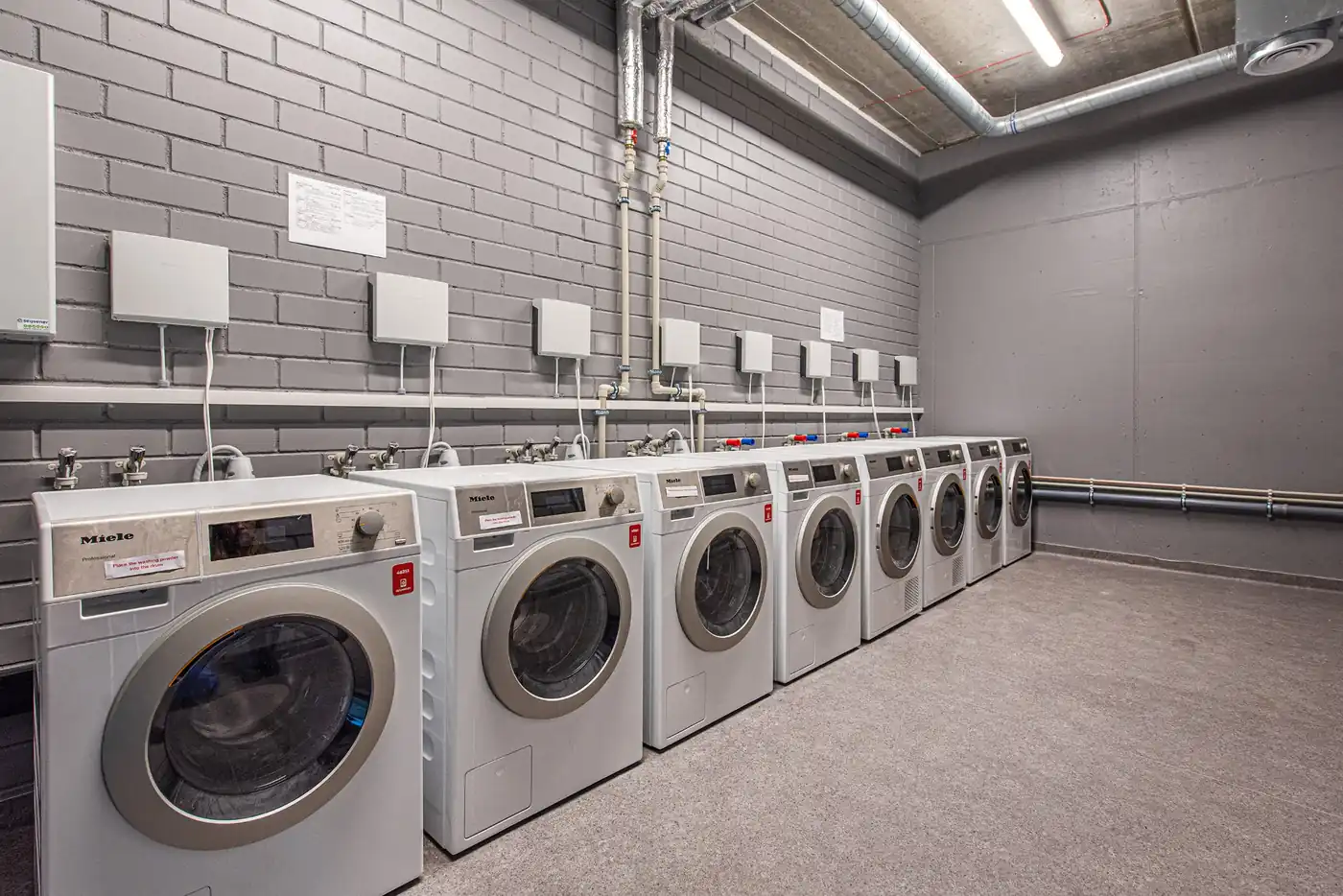 Shared laundry room in Vilnius student accommodation with multiple washing machines and dryers.