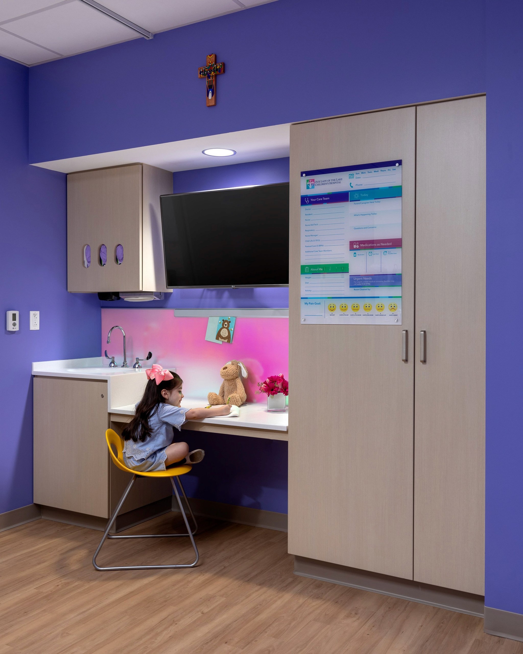 Girl at desk in brightly colored hospital room.