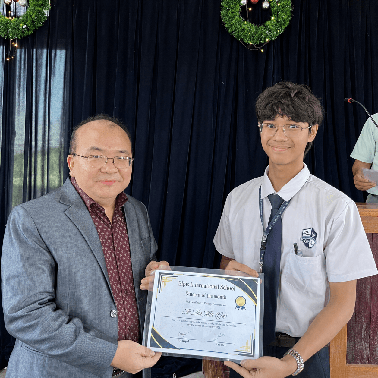 Founder of Elpis International School presenting a certificate to a student in Yangon, Myanmar