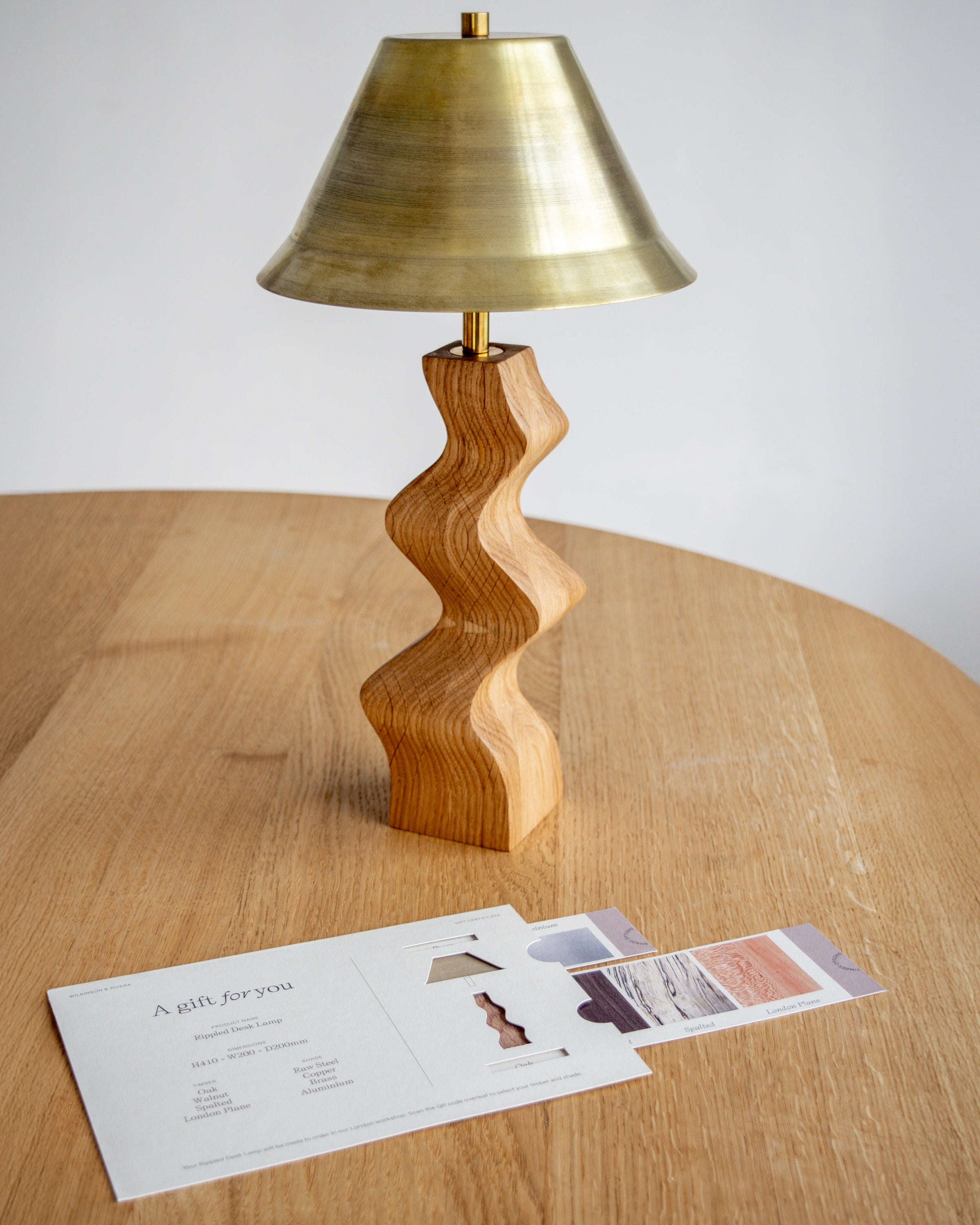Rippled Desk Lamp in Oak with Brass lampshade next to matching Wilkinson & Rivera gift card.