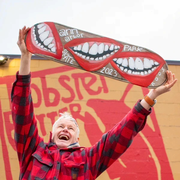 A photo of John Roos holding up a skateboard