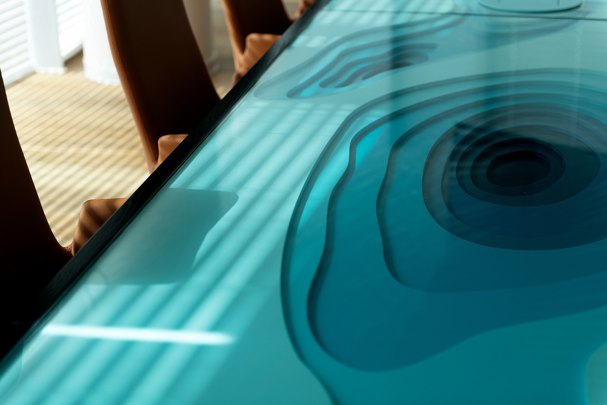 אומנות בזכוכית: מבט-על (Close Up) על שולחן הדירקטוריון, החושף את שכבות העומק של הים בגווני טורקיז ואת הטכניקה הייחודית של הזכוכית.