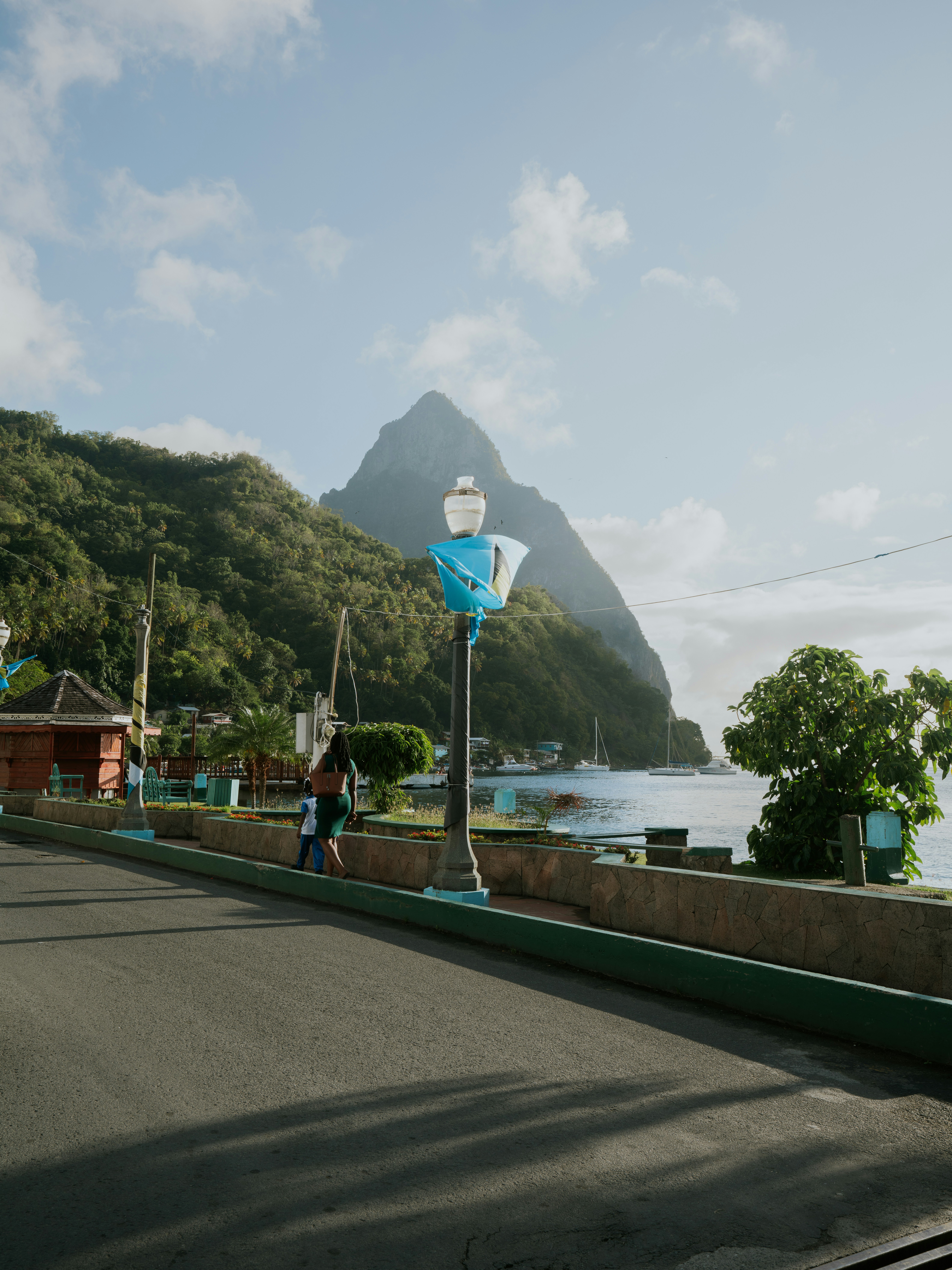 a woman walking down a street next to a mountain