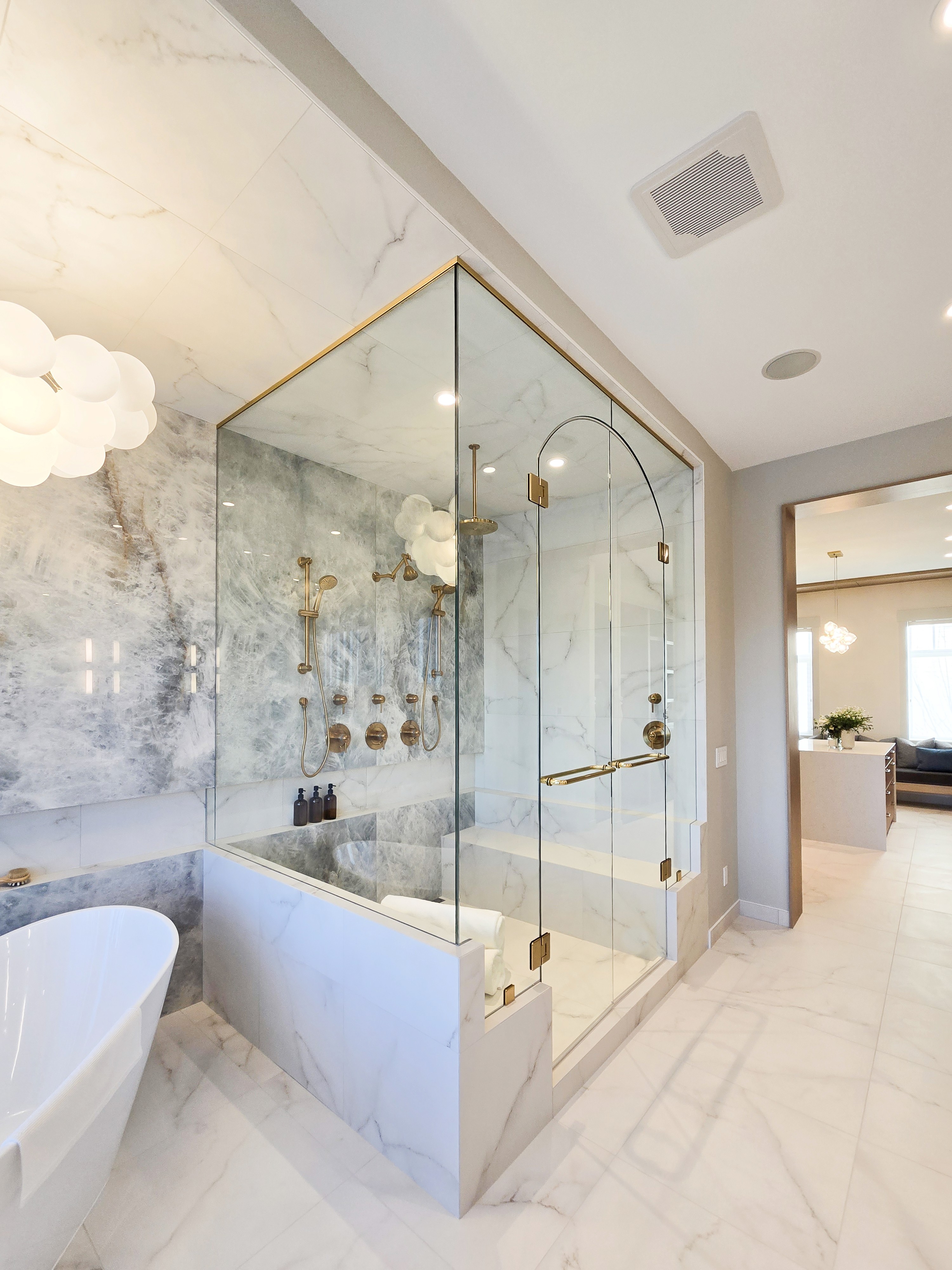 Image of Luxurious primary ensuite bathroom with marble tile, freestanding tub, and spacious walk-in shower by KHD Homes.