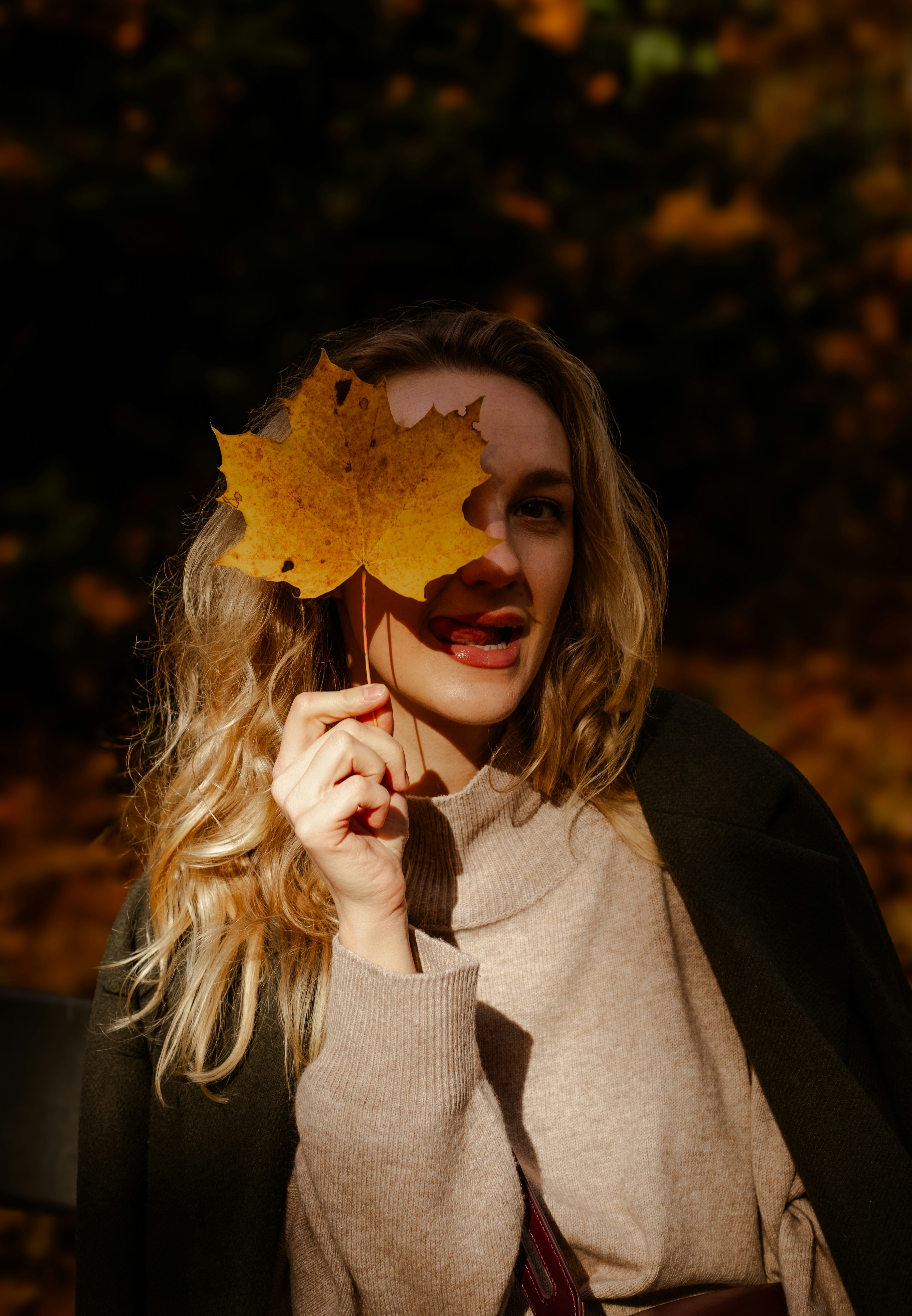 Woman holding a yellow leaf over her eye