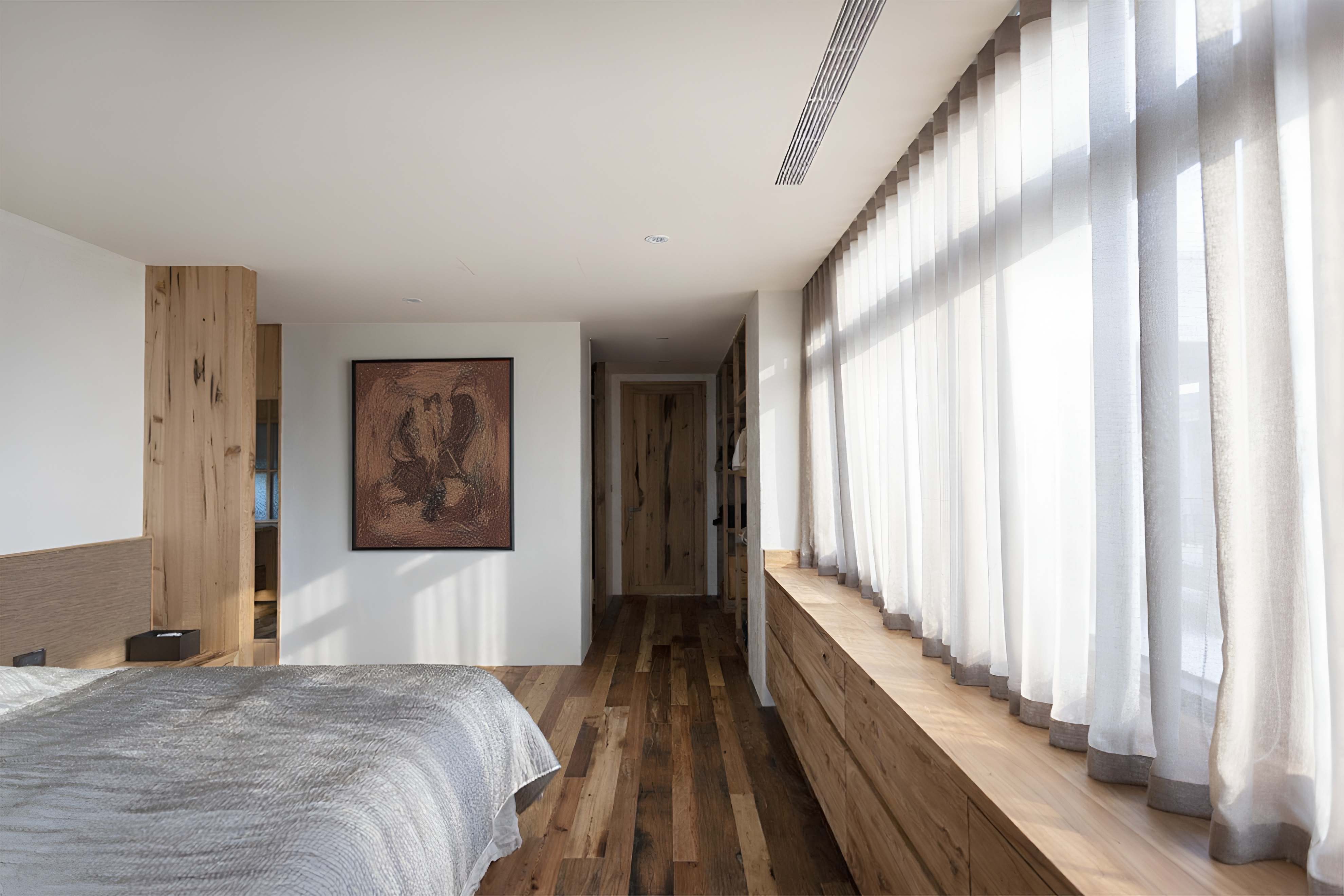 白色天花搭配原木家具與木地板構成溫暖臥室，大片窗簾柔化進入的自然光線