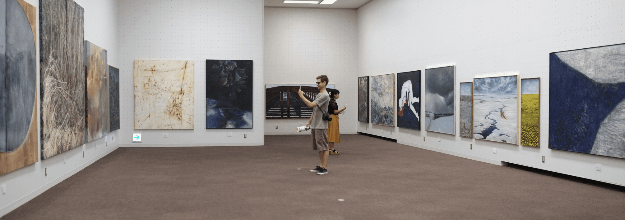 A visitor photographing a painting in an art gallery