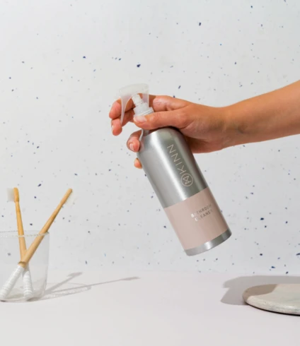 a person is holding a spray bottle over a cup