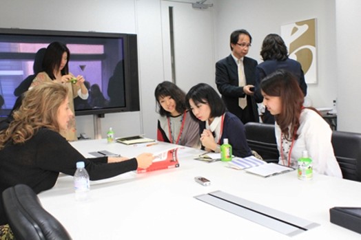 people sitting at a table with pens, rulers, and notepads