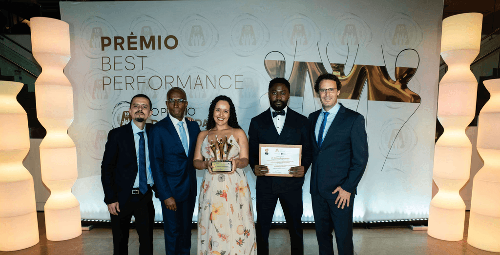 Executivos da CIX Citizen Experience posando com troféu ouro e certificado no palco do Prêmio Best Performance 2025