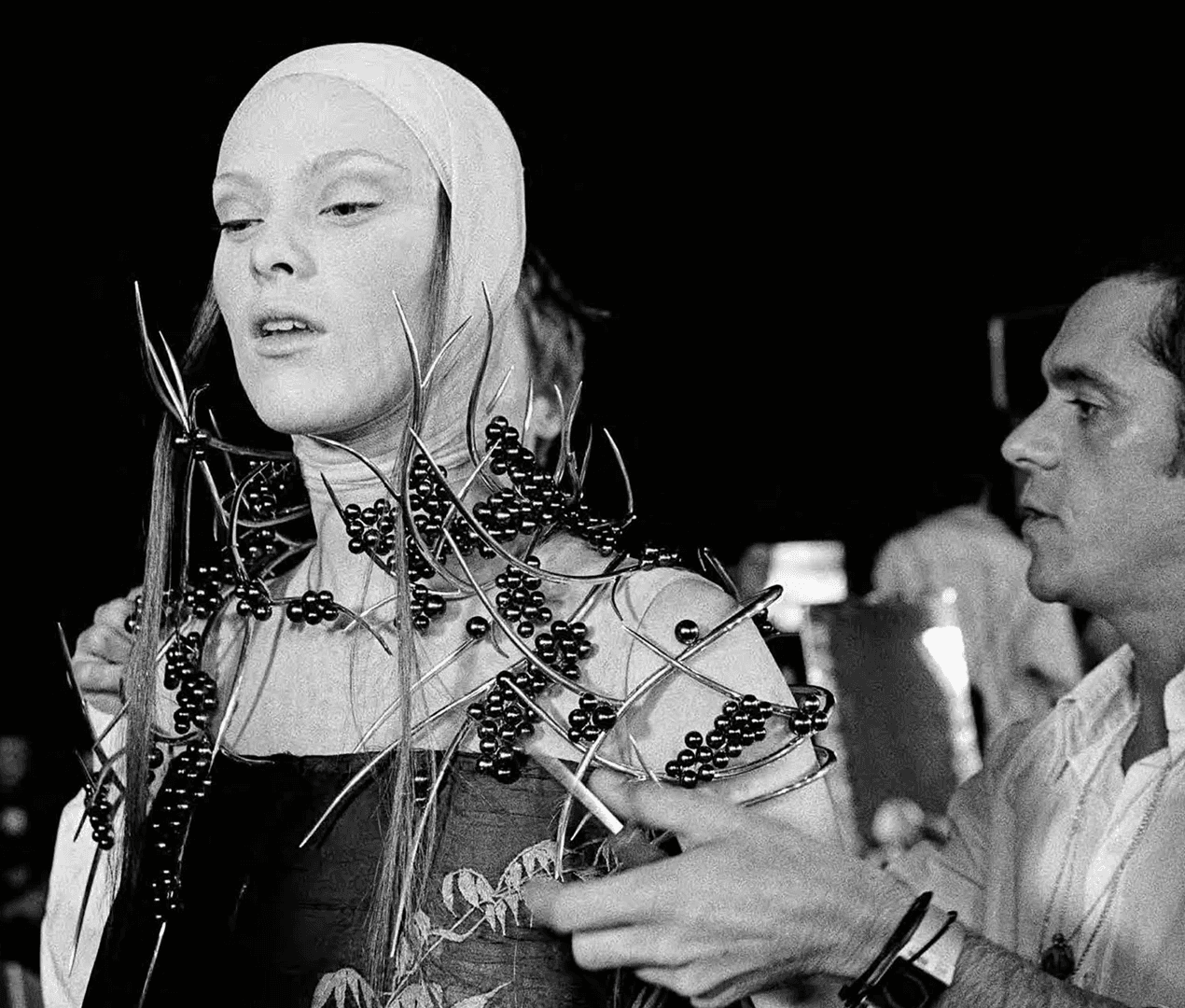 Backstage archival photo of a model wearing an intricate shoulder piece made of silver thorns and freshwater pearls, created by Shaun Leane for Alexander McQueen's VOSS show.