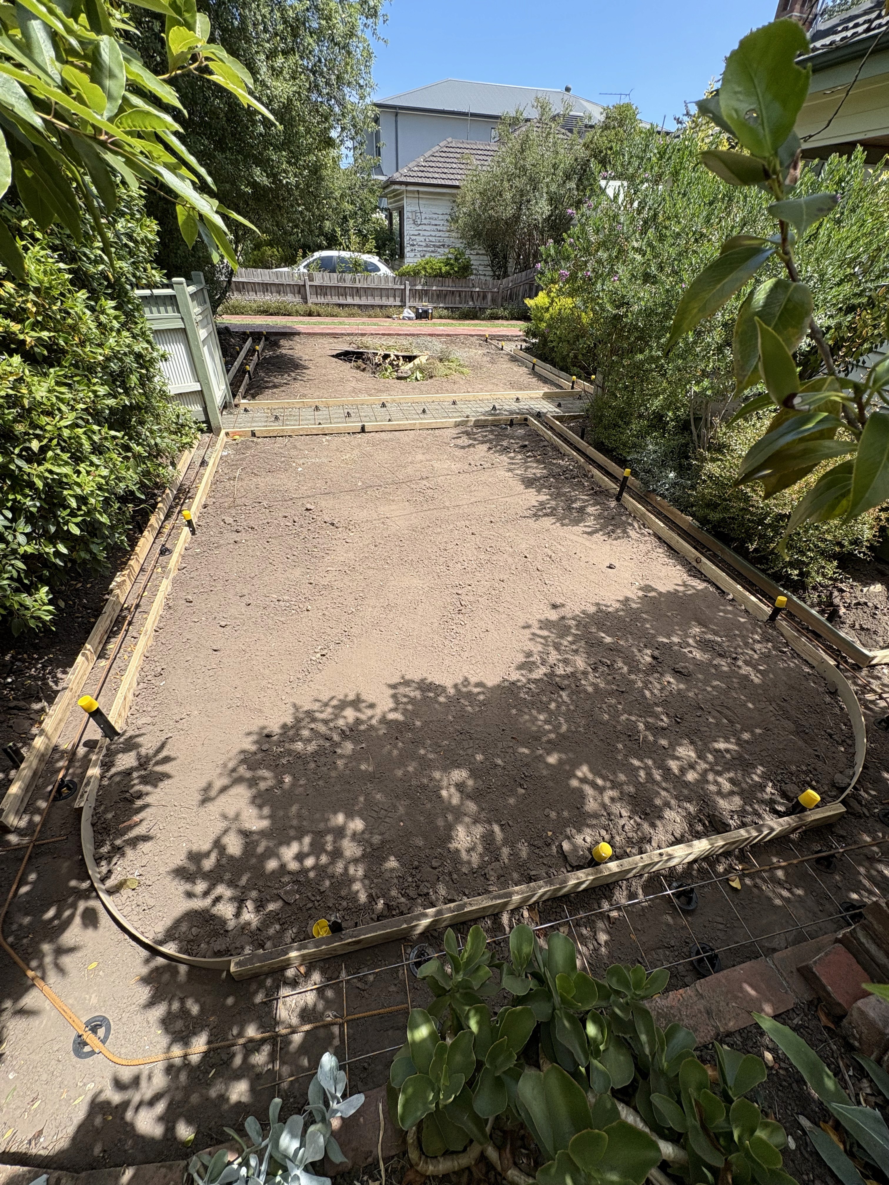 Backyard prepared for a concrete slab with forms and rebar mesh.
