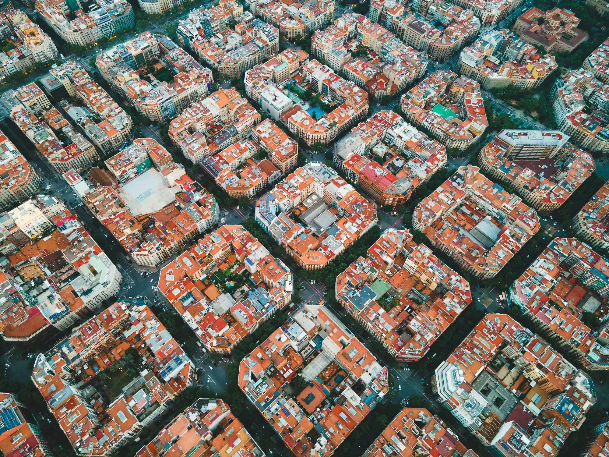 An aerial image of the Eixample neighborhood of Barcelona, with perfectly uniform city blocks captured from above.