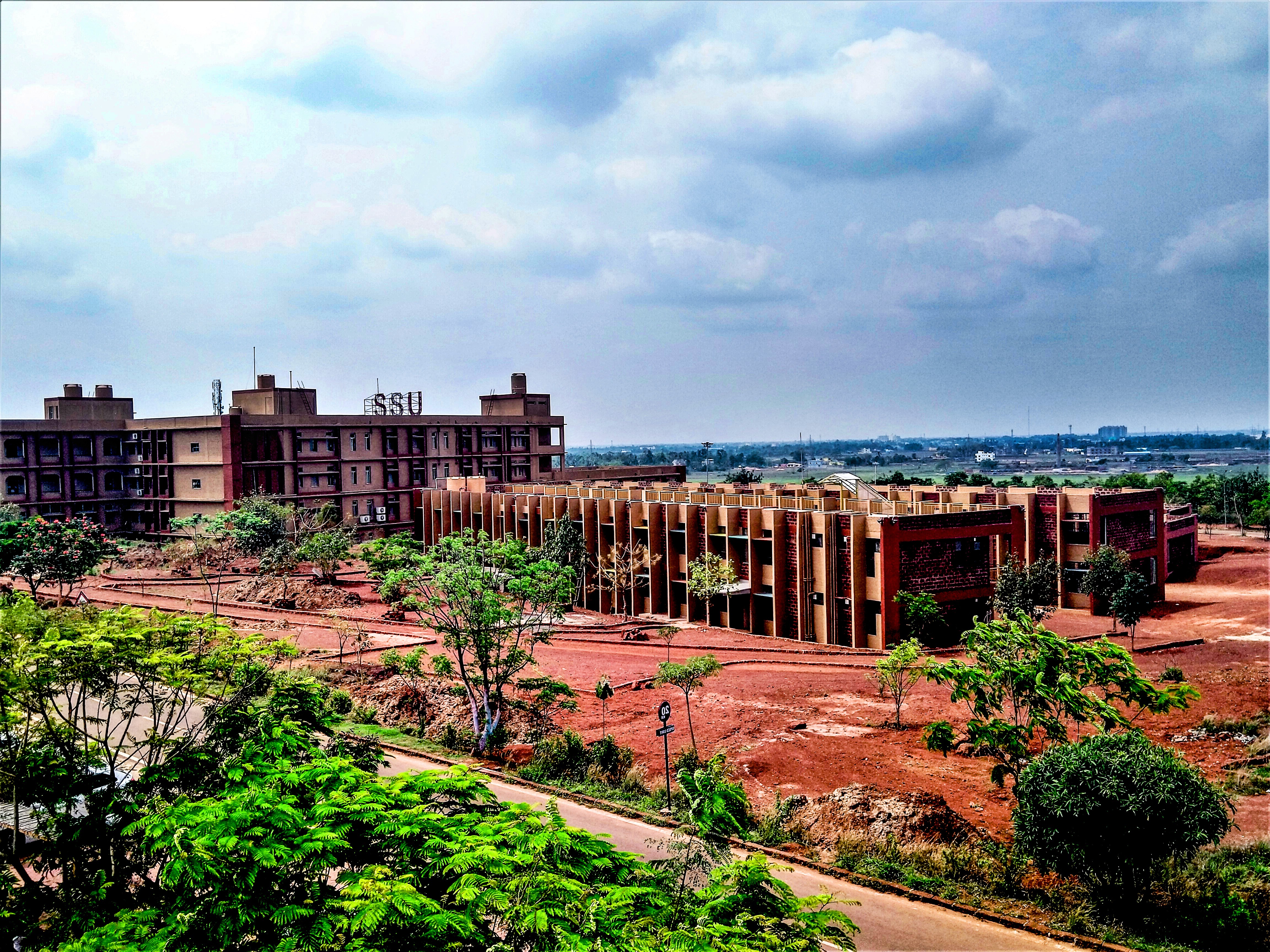 Aerial view of a winding road cutting through rocky terrain and sandy landscape.