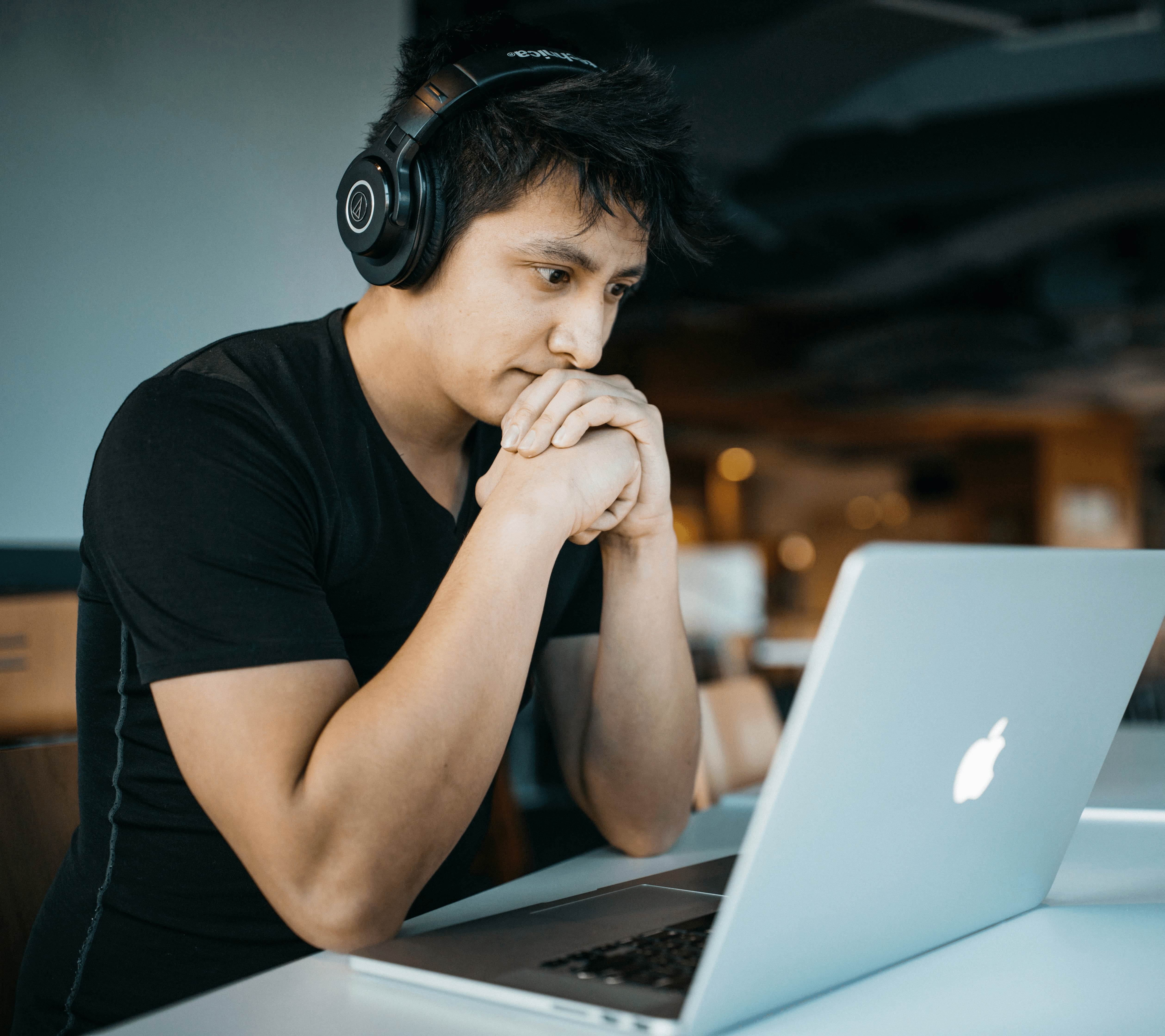 man wearing headphones while sitting on chair in front of MacBook