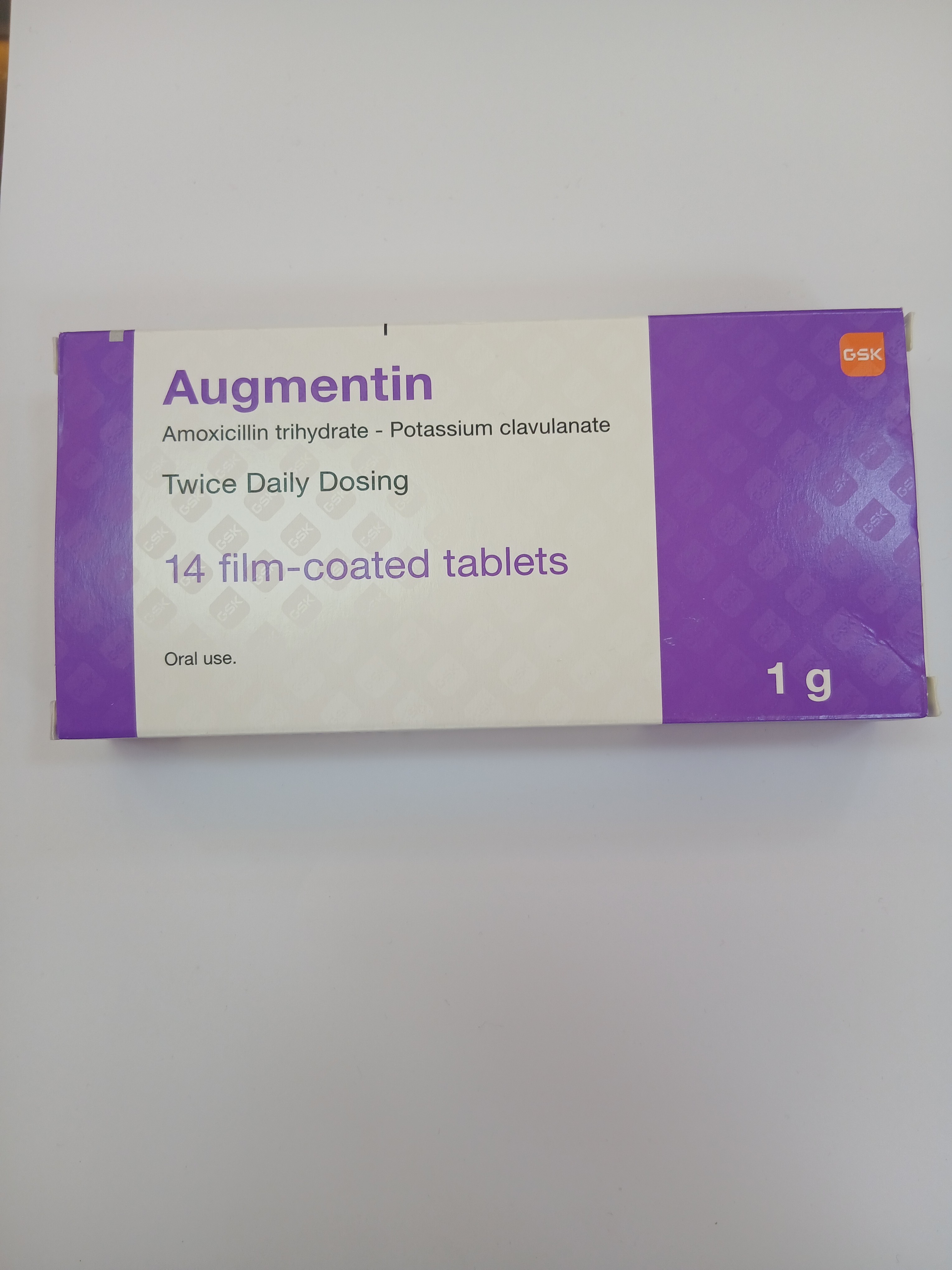 Augmentin Amoxicillin trihydrate - Potassium clavulanate 1g, 14 film-coated tablets for twice daily dosing in a white and purple cardboard box.