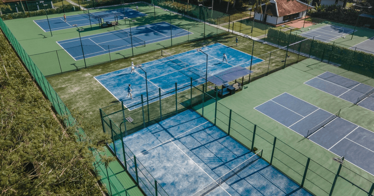 Multiple outdoor padel and tennis courts surrounded by greenery.
