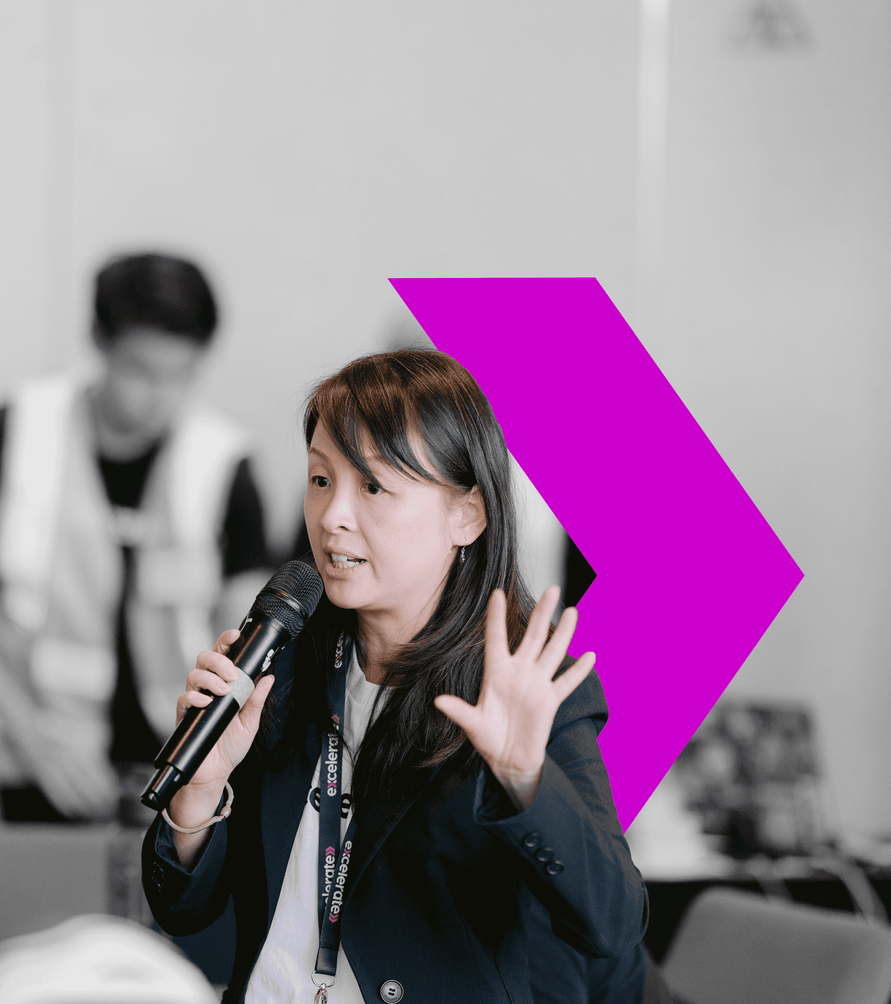 A professional woman in a business suit speaks confidently into a microphone, embodying leadership and expertise.