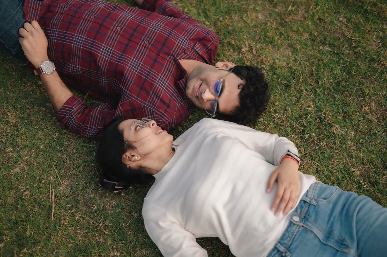 Couple lying on their backs on short grass seen from above