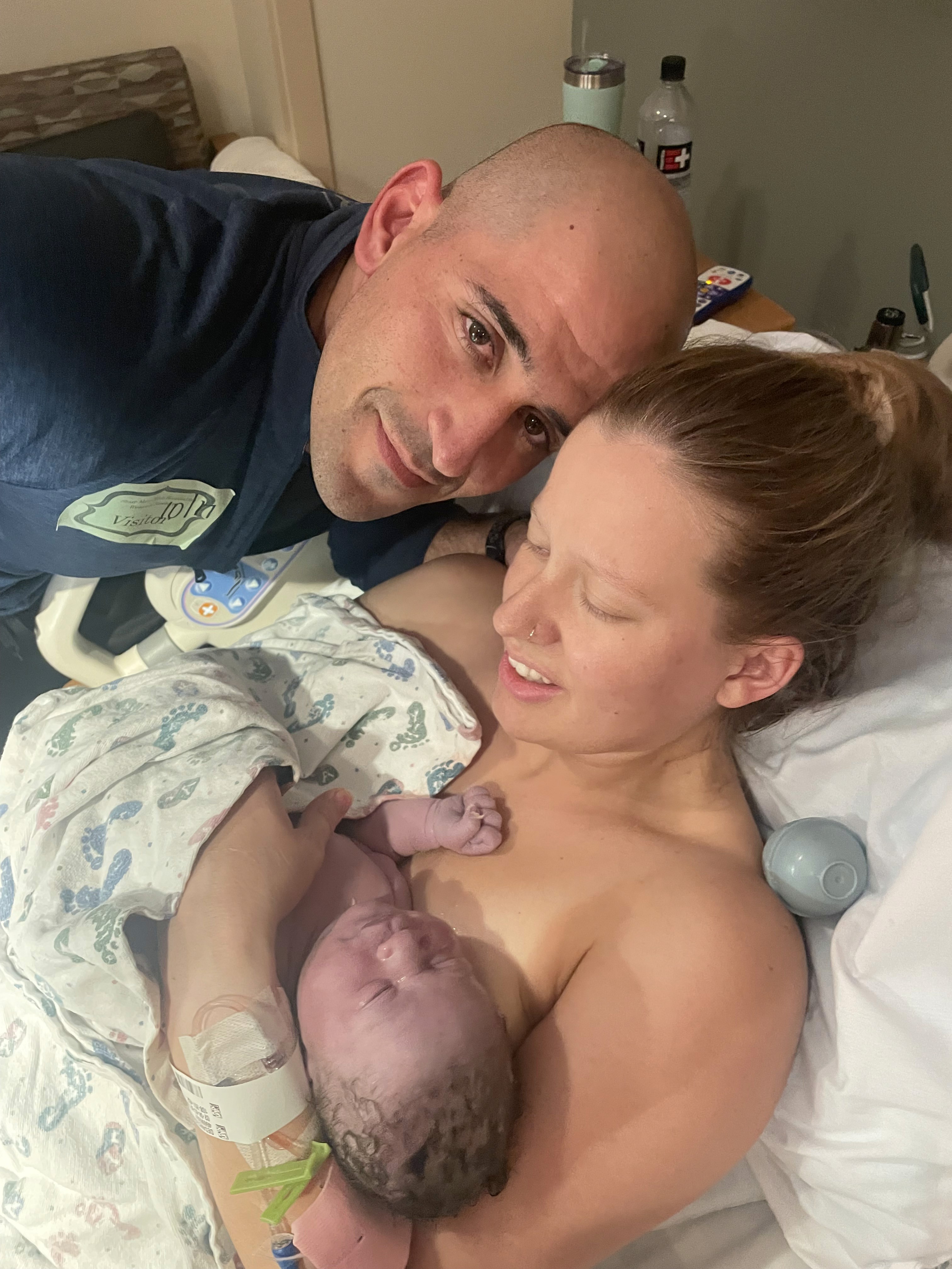 a woman and man holding their newborn son in a hospital bed