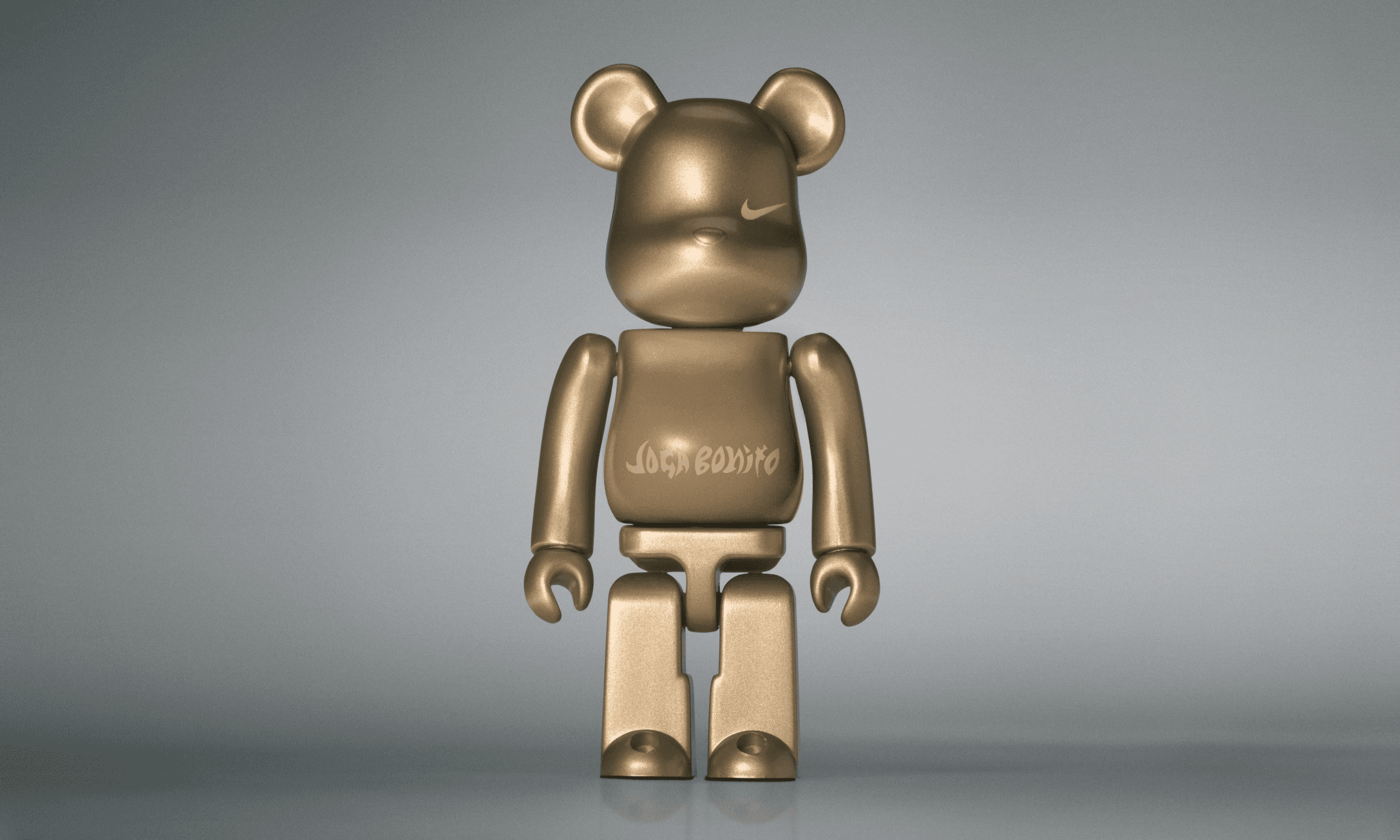 A single 3.5” tall Bre@rbrick/Nike toy created to commemorate the beautiful game. The toy is painted in gold and stands in the center of the frame in front of a dark grey background.