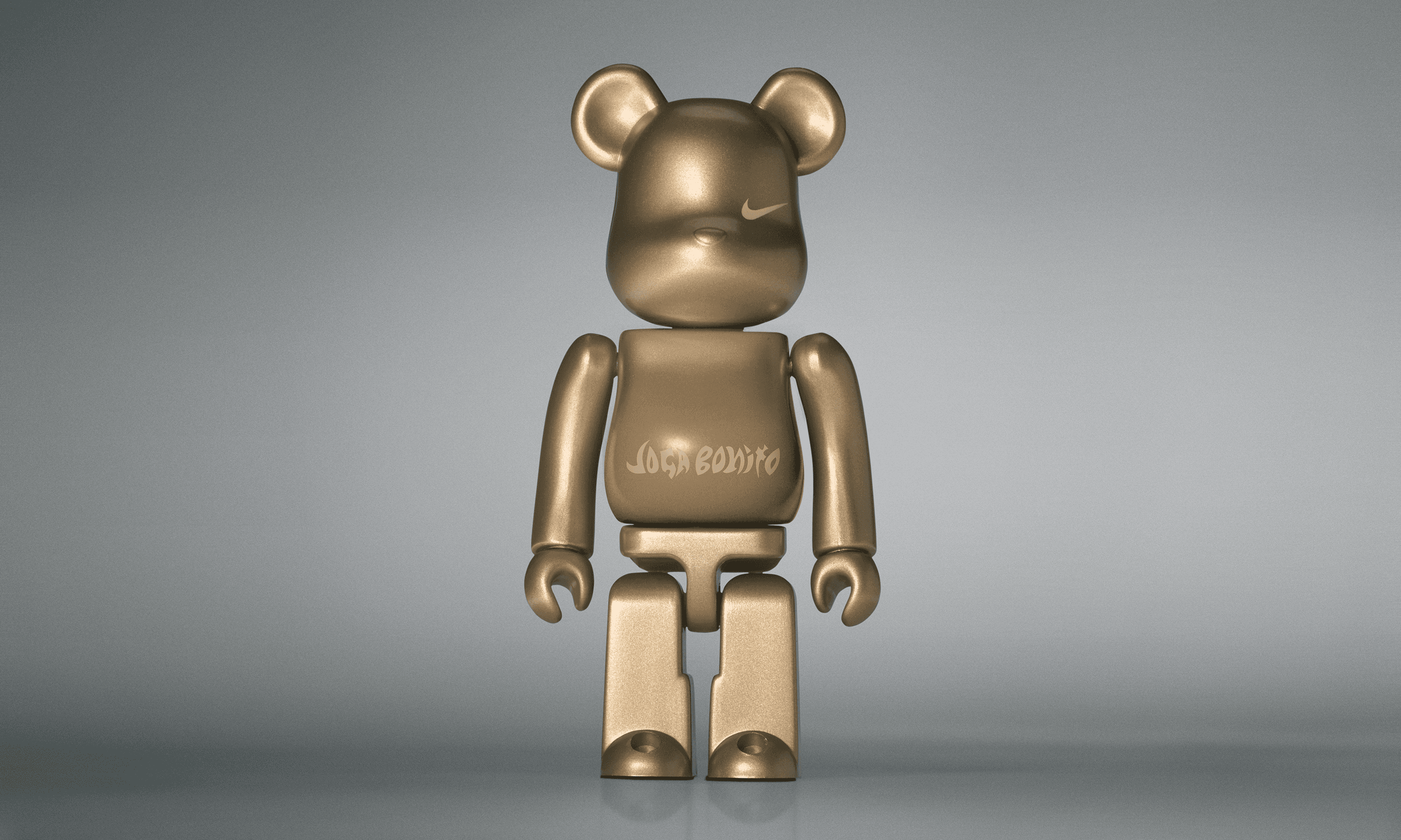 A single 3.5” tall Bre@rbrick/Nike toy created to commemorate the beautiful game. The toy is painted in gold and stands in the center of the frame in front of a dark grey background. 