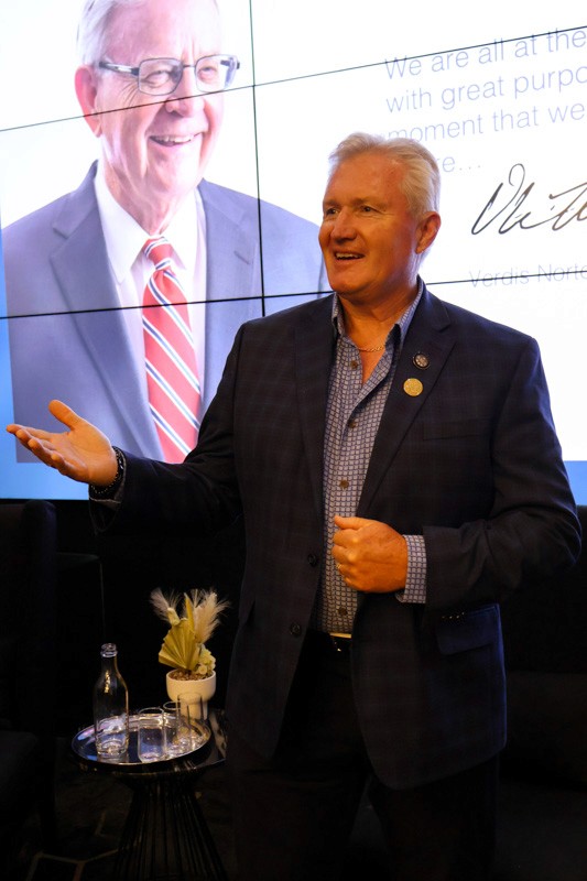 man in a blue suit stands in front of a presentation