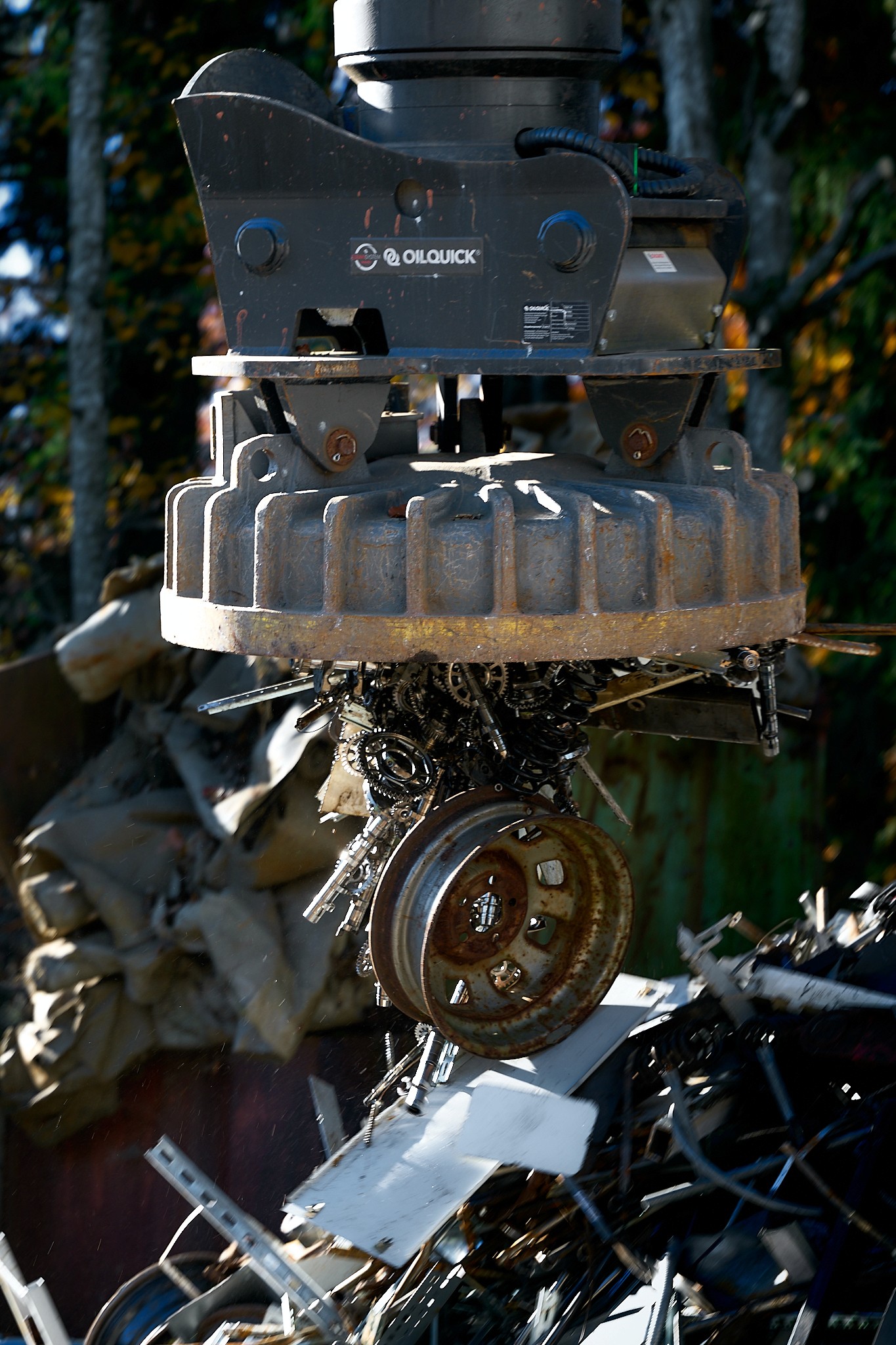 Ein Kran hebt einen Schrottberg mit Magnet. Metallschrott mit Rädern, Karosserieteilen und Elektronikschrott.