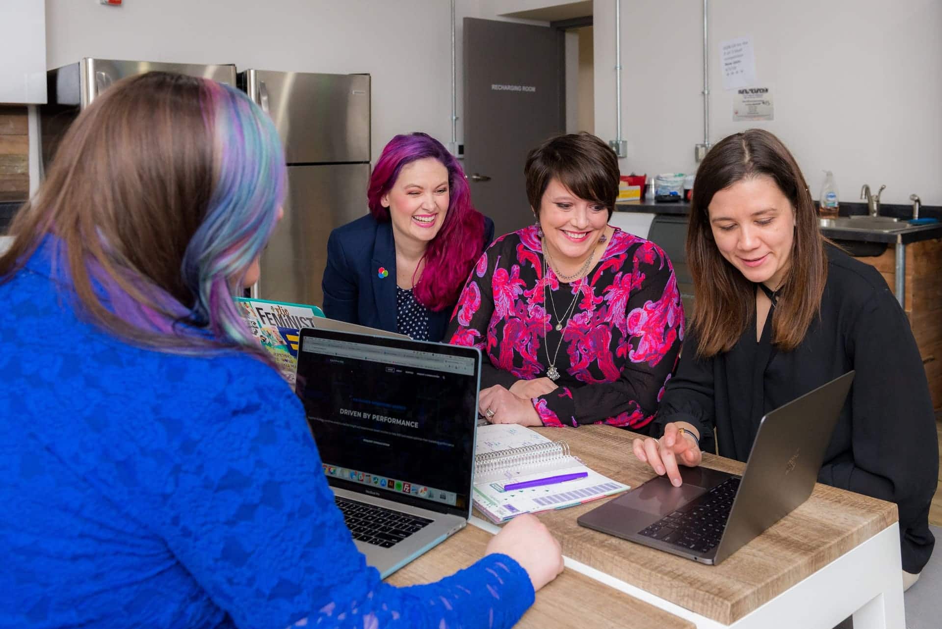 Women collaborating in a modern office setting with laptops and notebooks.