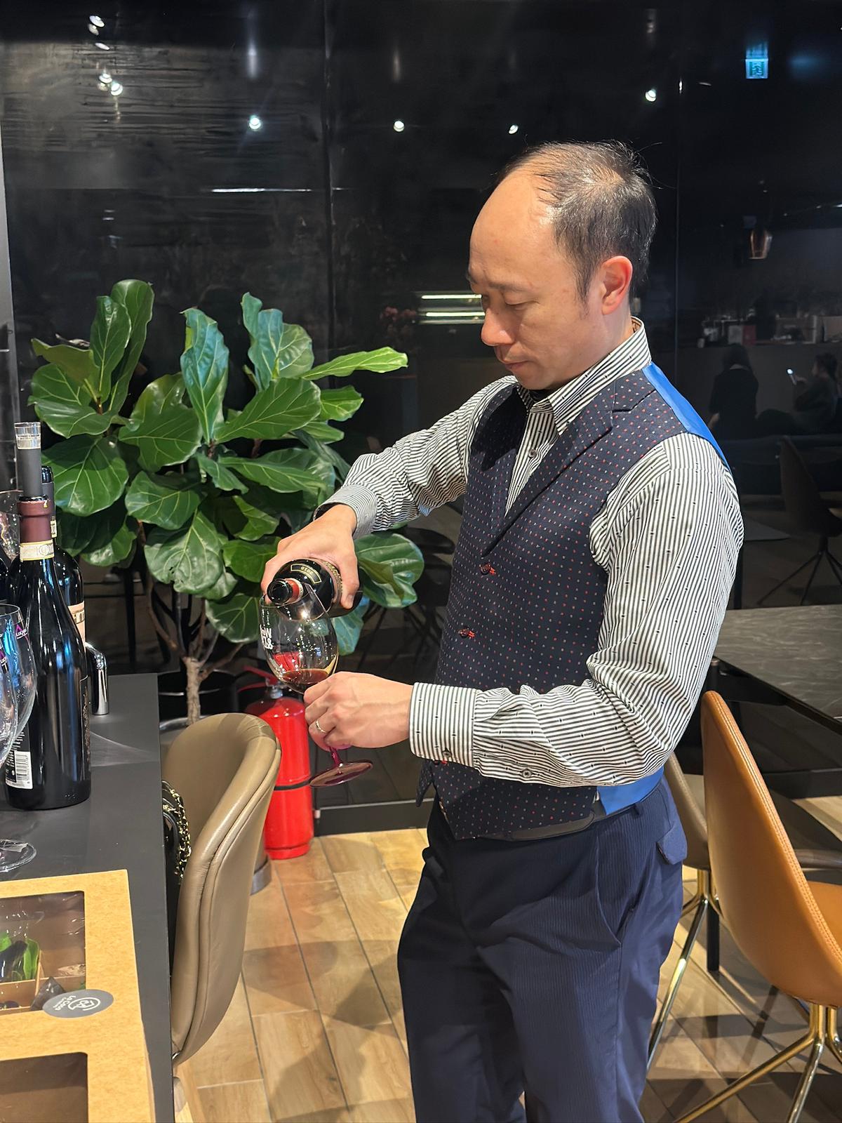 Professional WSET-certified sommelier pouring wine at a corporate event, providing expert guidance and tasting notes