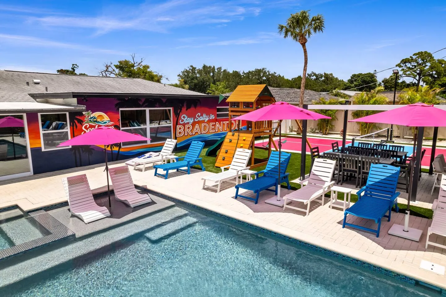 Pool with pink umbrellas, playset and house mural at Salty House, Bradenton, Florida