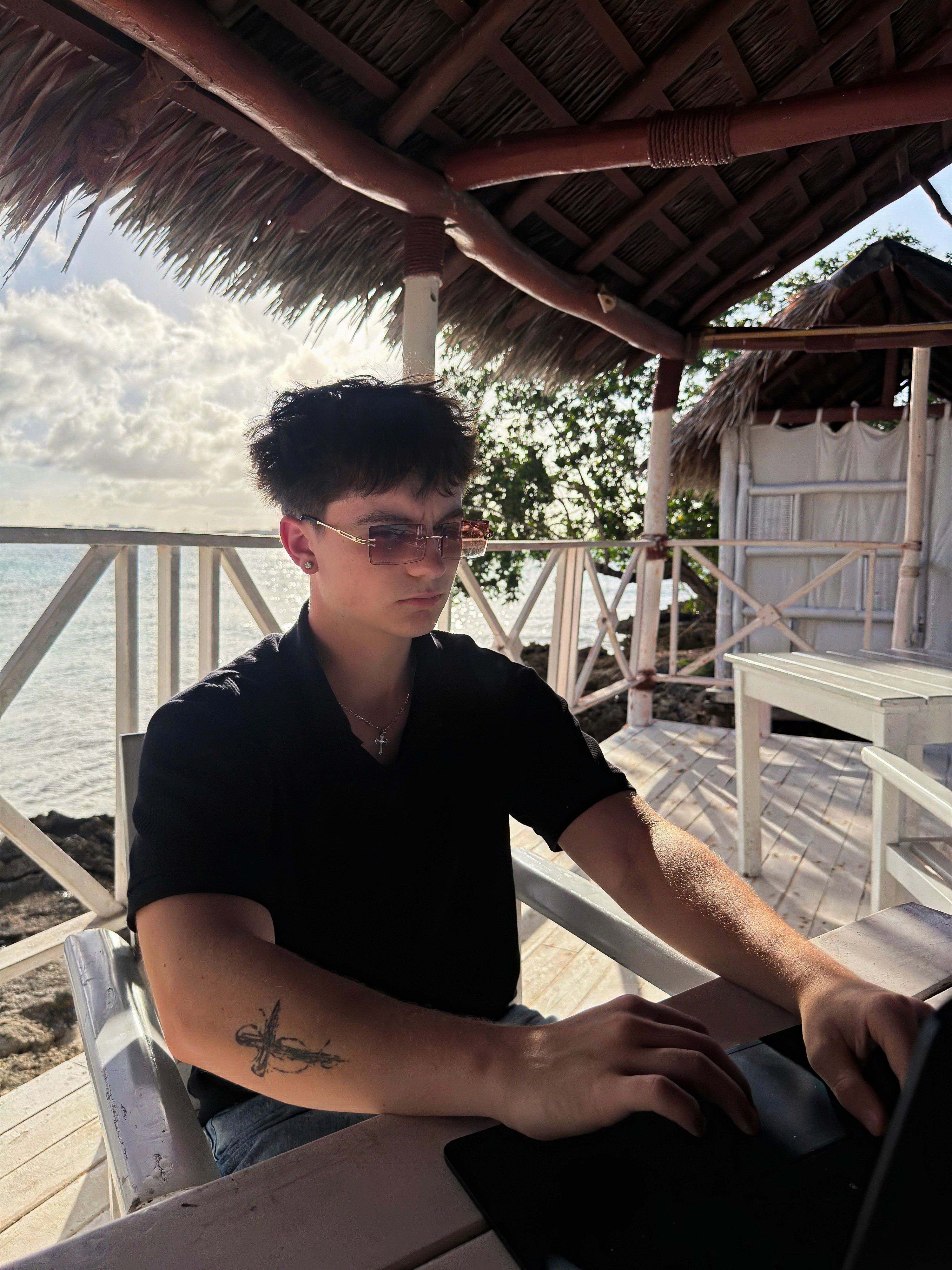Woman in a stylish orange visor, yellow earrings, and a navy lace top against a blue backdrop. Her expression is poised, with bold red lipstick.
