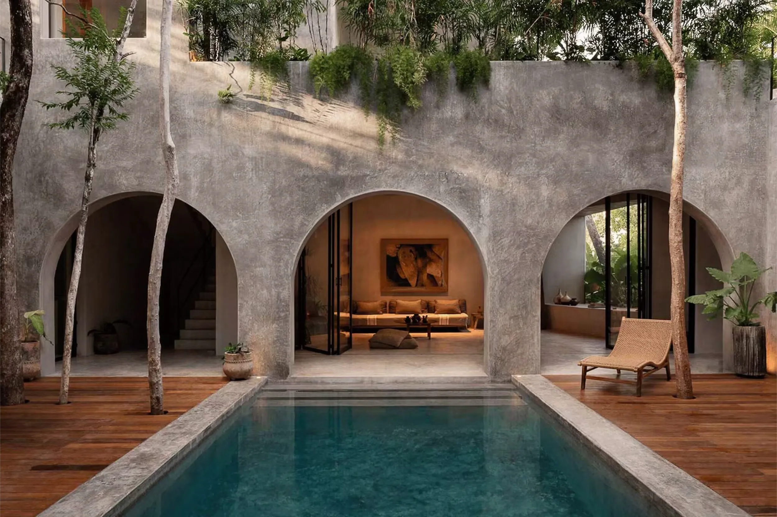 Central courtyard featuring brutalist concrete arches, a swimming pool, and native vegetation integrating nature into the residential architecture.