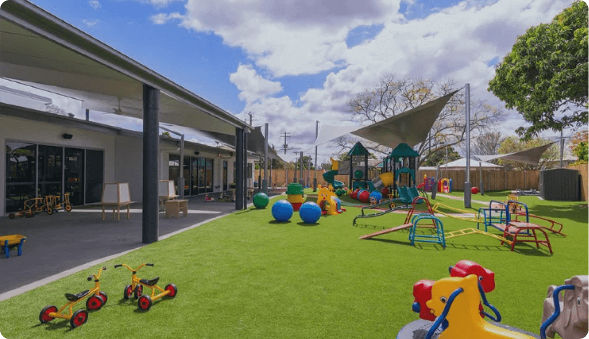 Outdoor playground at Kaleidoscope Kids Booval childcare centre with slides, climbing equipment and shaded areas for active play.