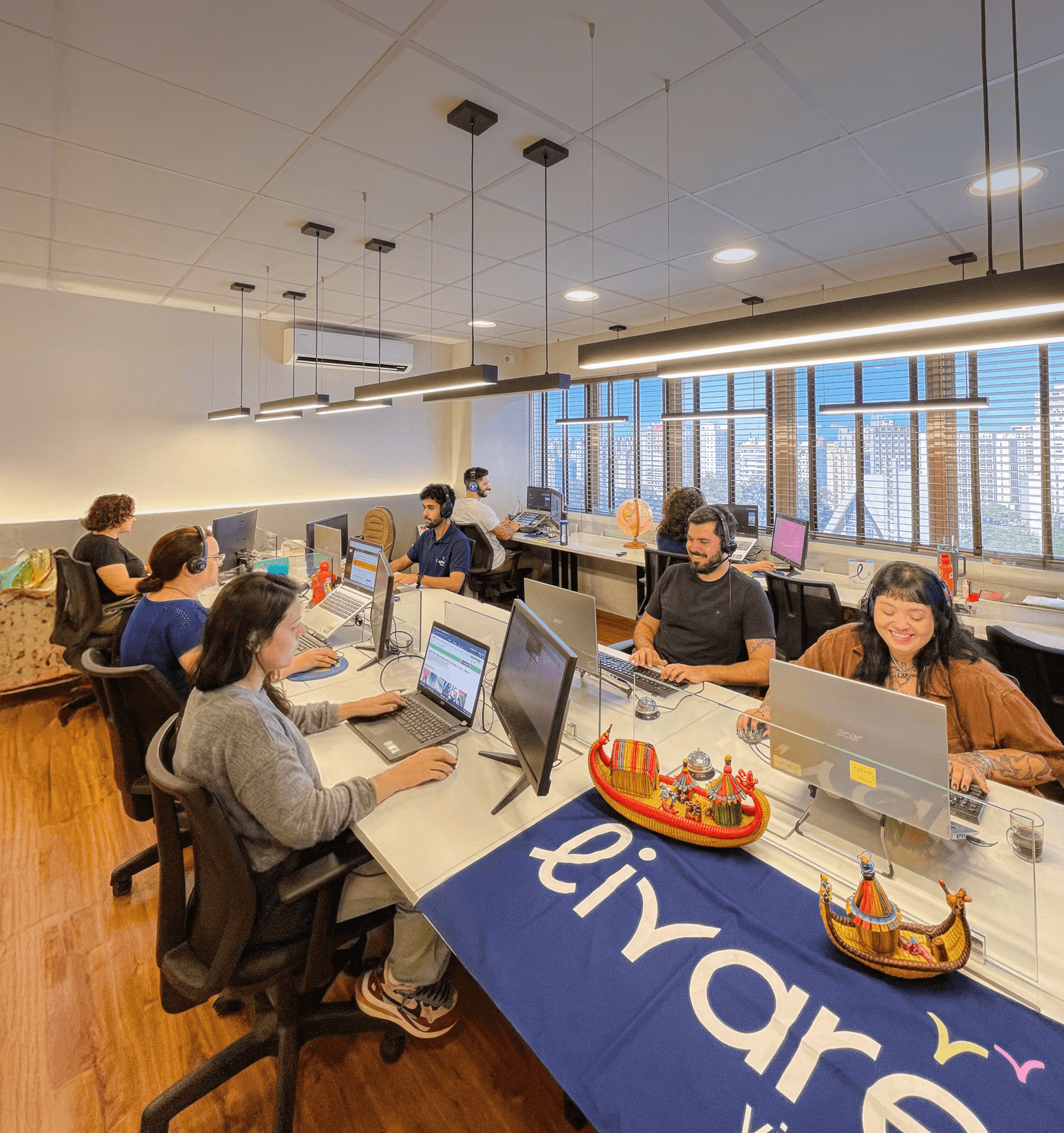 Equipe da Livare Viagens trabalhando em escritório moderno, com colaboradores em estações de trabalho e ambiente corporativo organizado