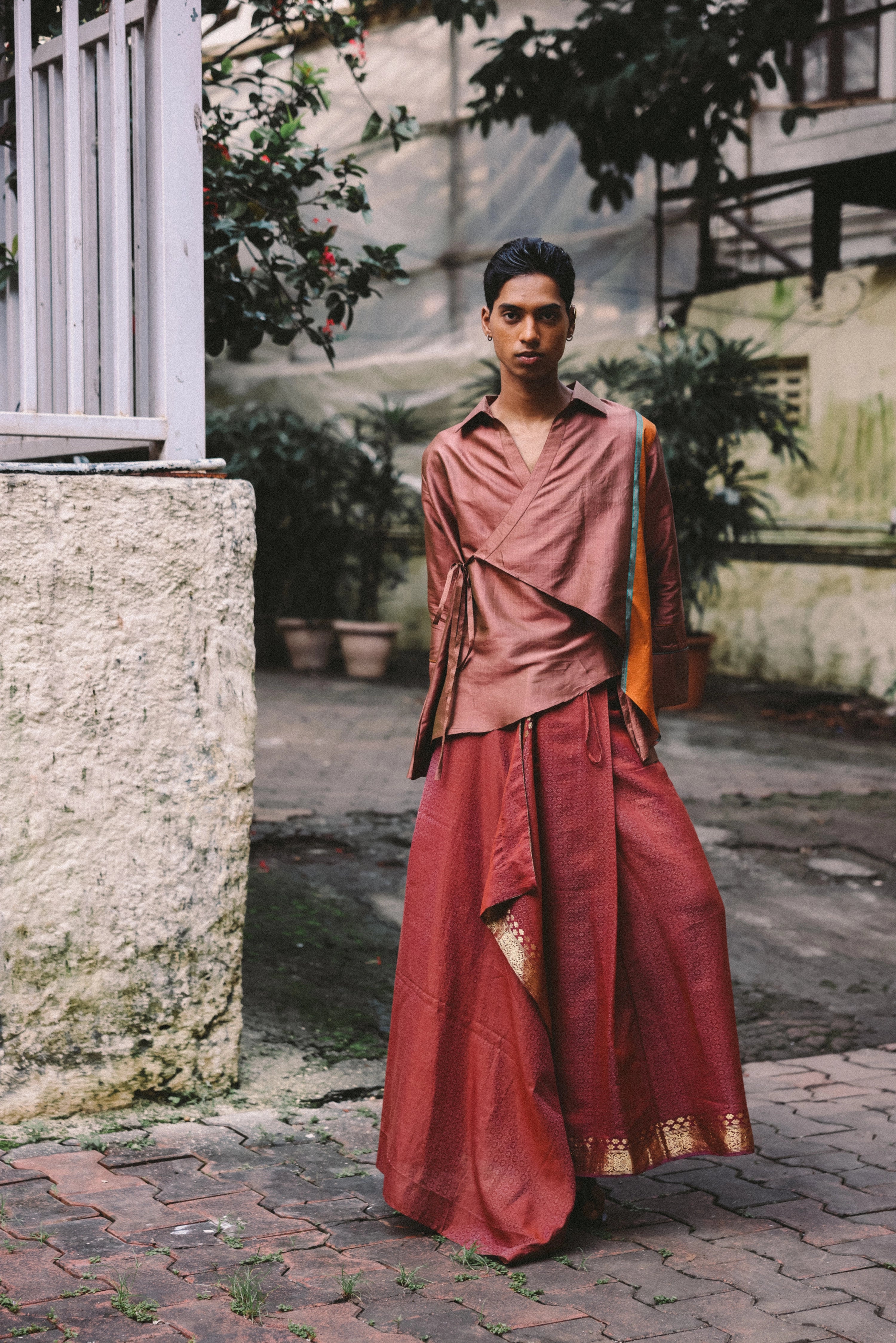 Rajasthani-inspired wrap top in rose silk blend with asymmetric hem and tie closures — modern reinterpretation of the traditional angrakha kurti