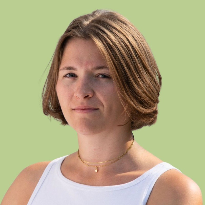 portait photo of a woman with short hair looking at the camera and smiling, wearing a white tank top