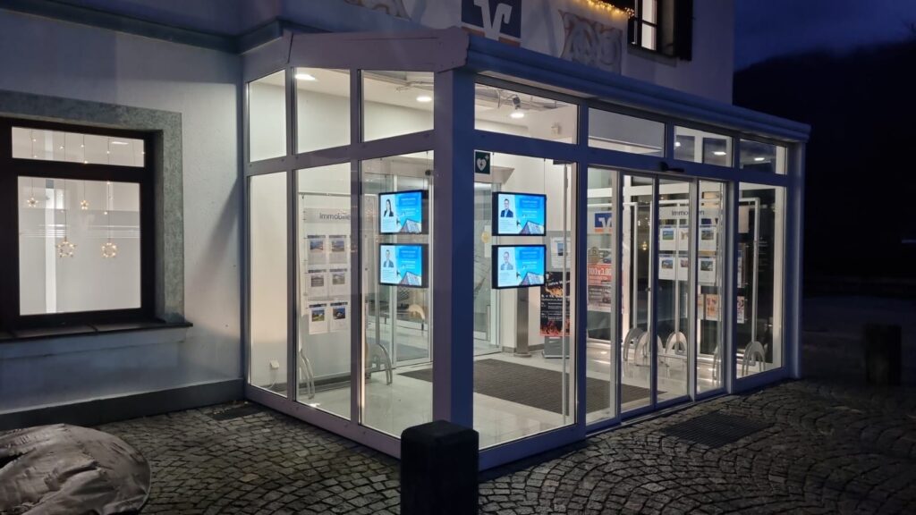 Modern, glass-fronted bank building entrance at night.